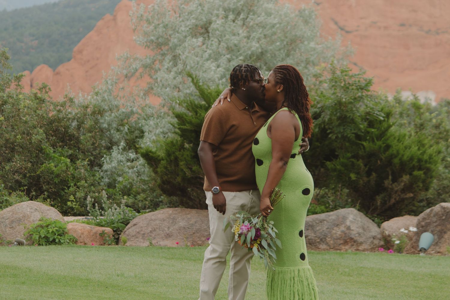 A romantic moment captured on manicured lawn with red rock formations in the background.