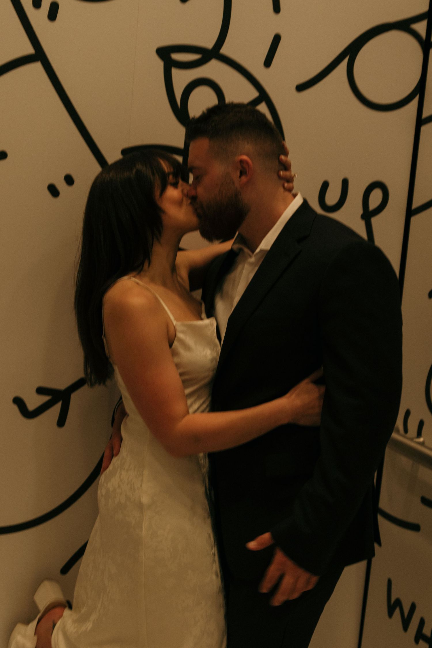 Romantic dance sequence against a wall with artistic black drawings.