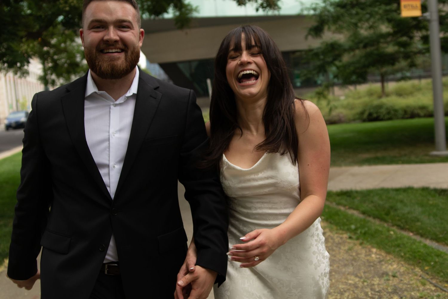 Joyful couple walking outdoors and laughing together on urban sidewalk.