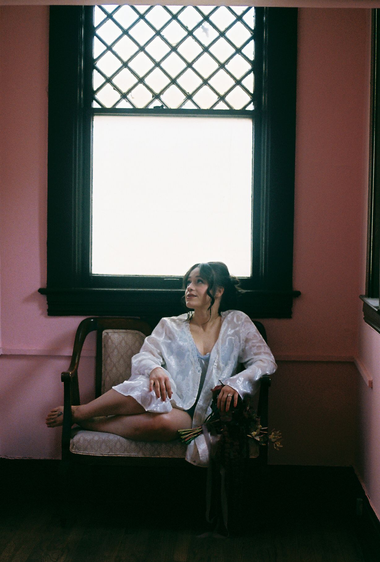 Dreamy boudoir scene with morning light streaming through latticed window.