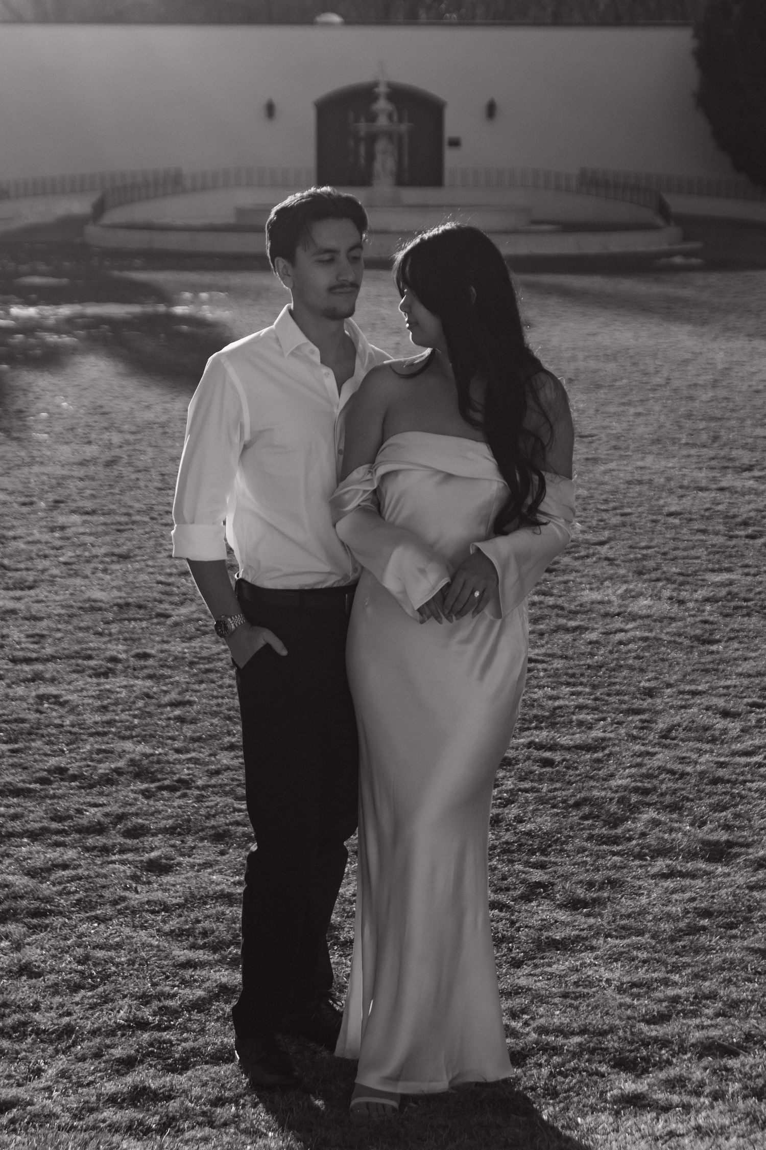 A black and white photo of a couple embracing on a frost-covered lawn.