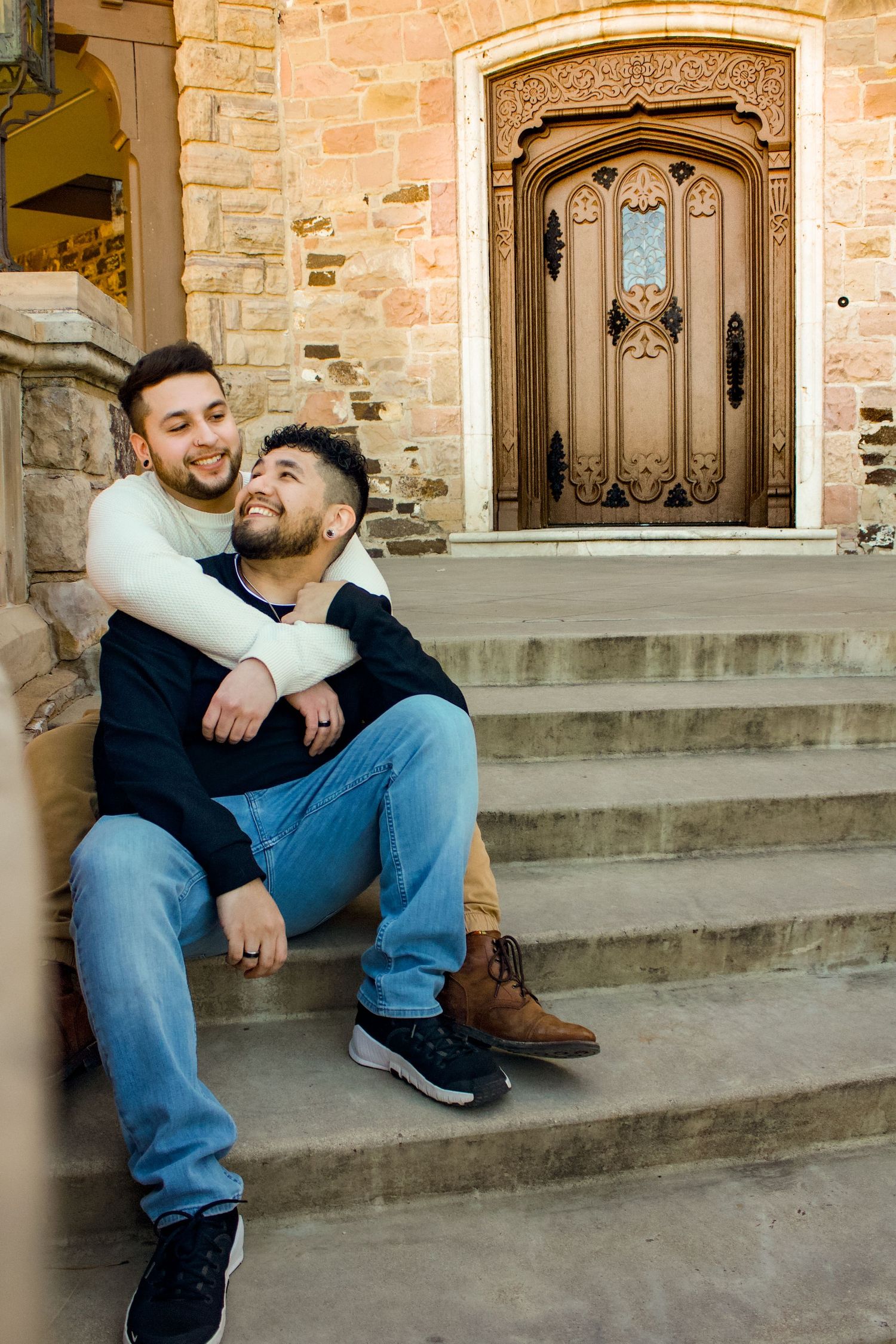 A couple sharing tender moments while sitting on stone steps in front of an ornate doorway.