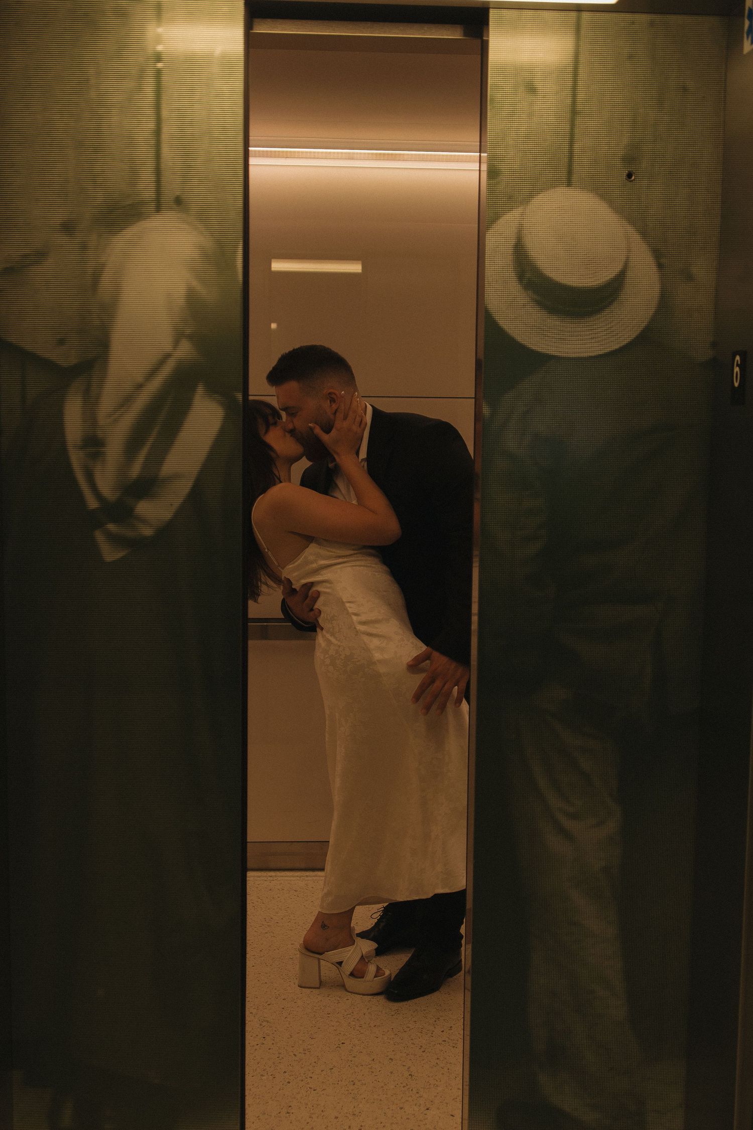 Artistic photograph through elevator doors showing a couple's intimate moment.