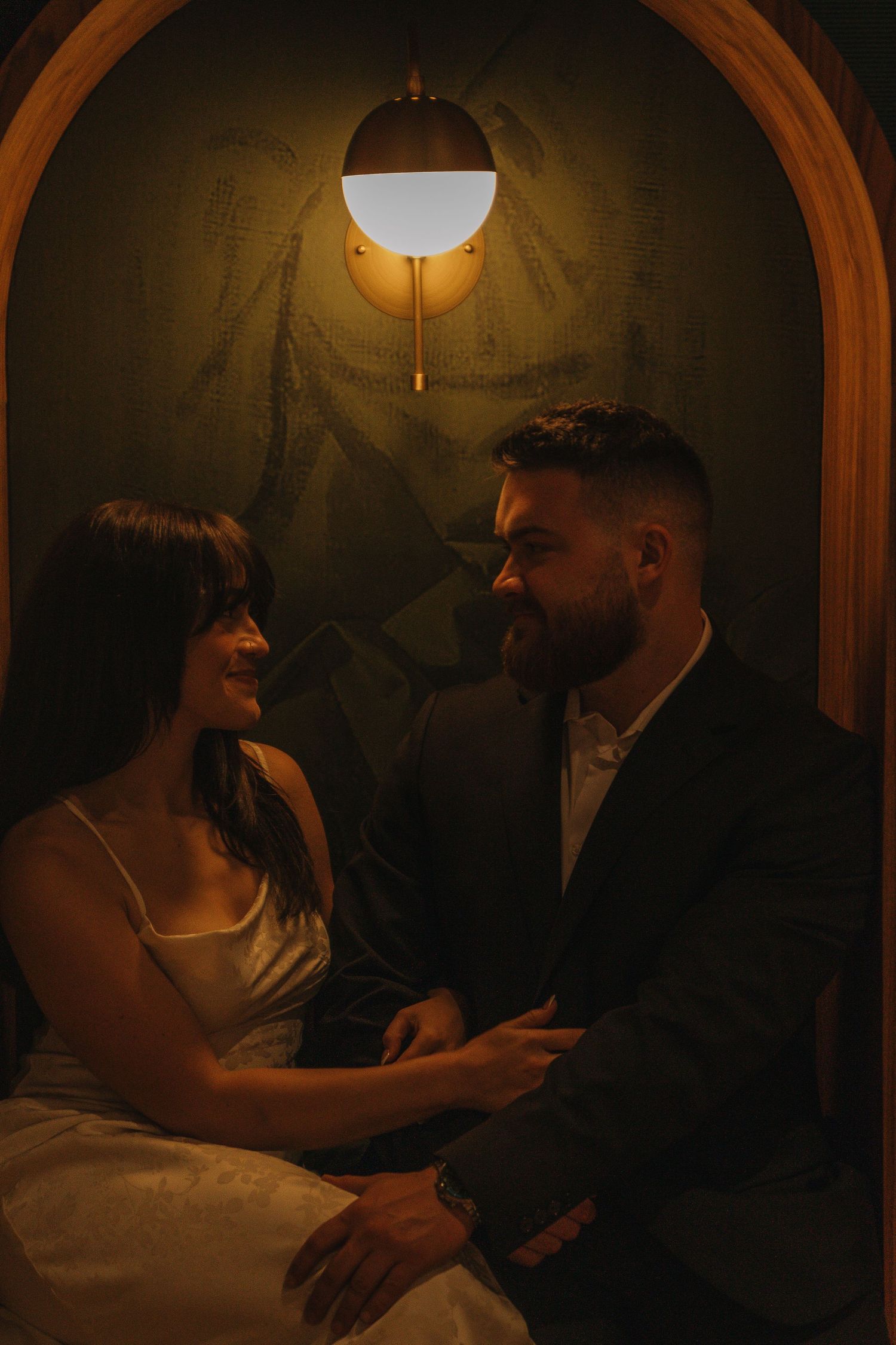 Romantic couple in an intimate candlelit setting with vintage wallpaper.