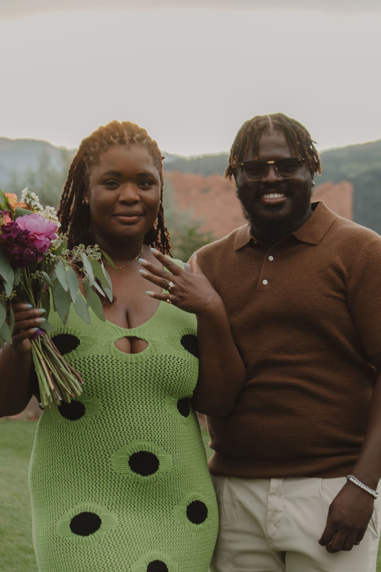A couple shares intimate moments in a garden while wearing contrasting brown and lime green outfits.