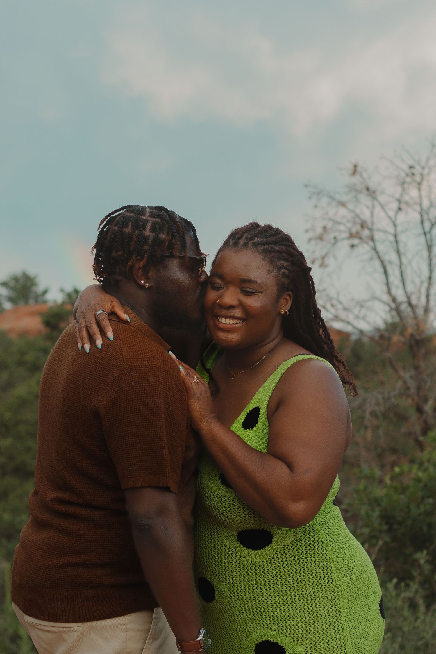 Two people share an intimate moment outdoors, one wearing a striking lime green polka dot dress.
