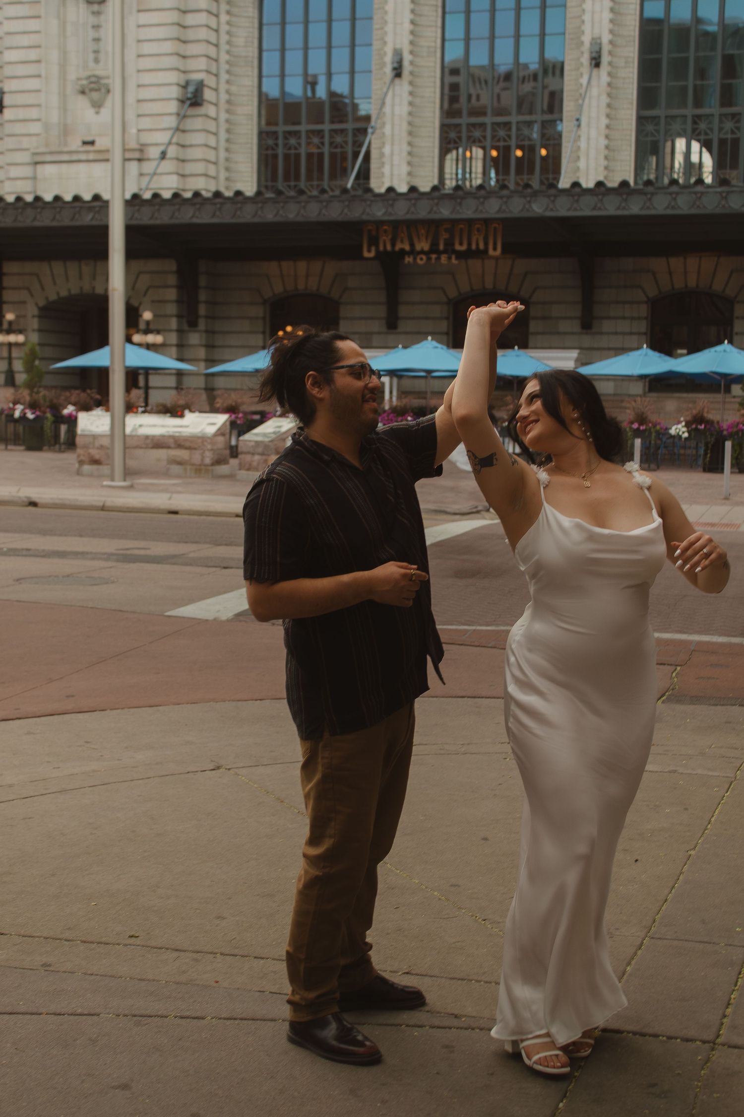 A couple dances playfully outside a historic building with classical architecture.