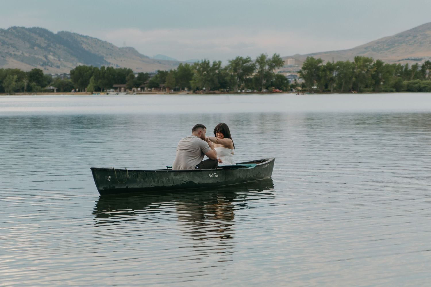 Scenic mountain lake view with distant silhouette of couple in canoe.