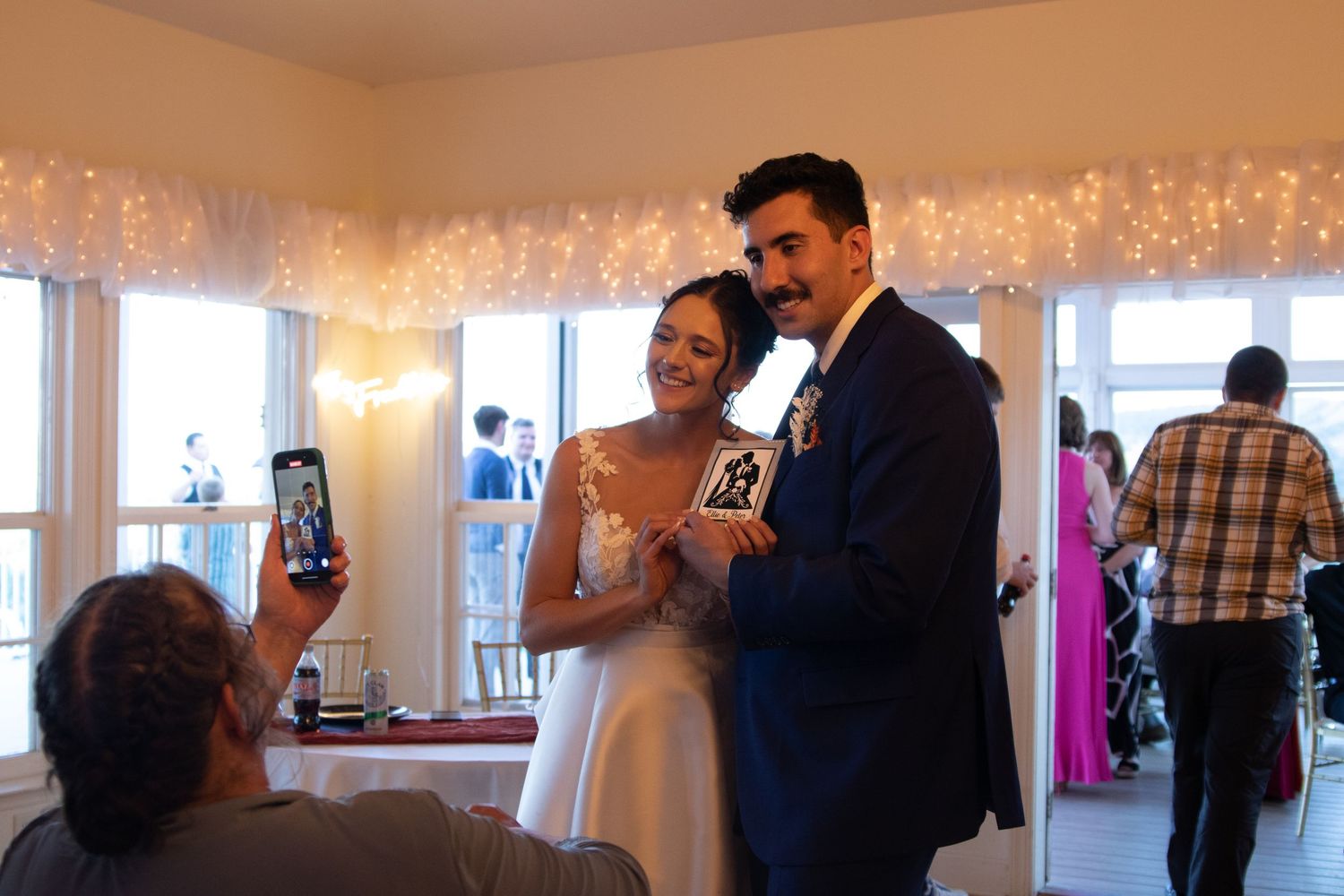 Warm-lit reception space with fairy lights and dancing couples.