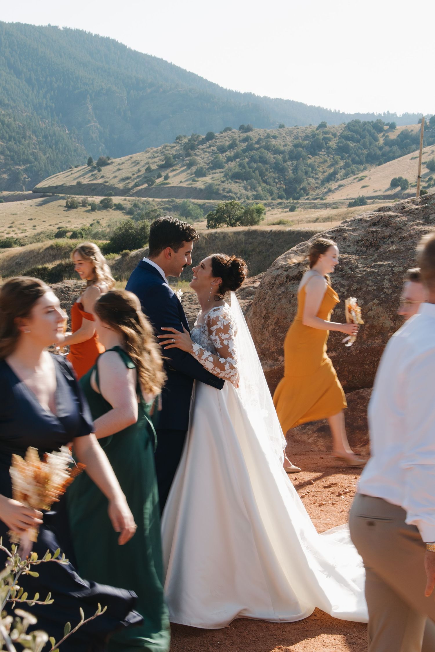 Wedding party members in formal attire celebrate on a scenic mountain overlook.