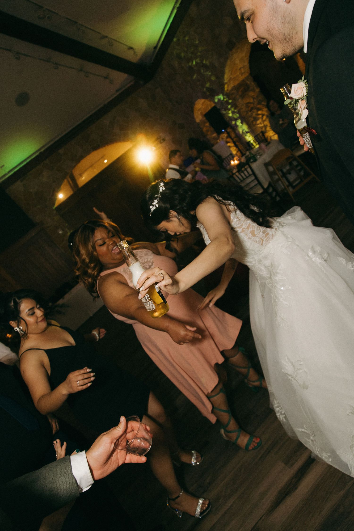 Bride and groom dance energetically with guests on the wedding reception dance floor.