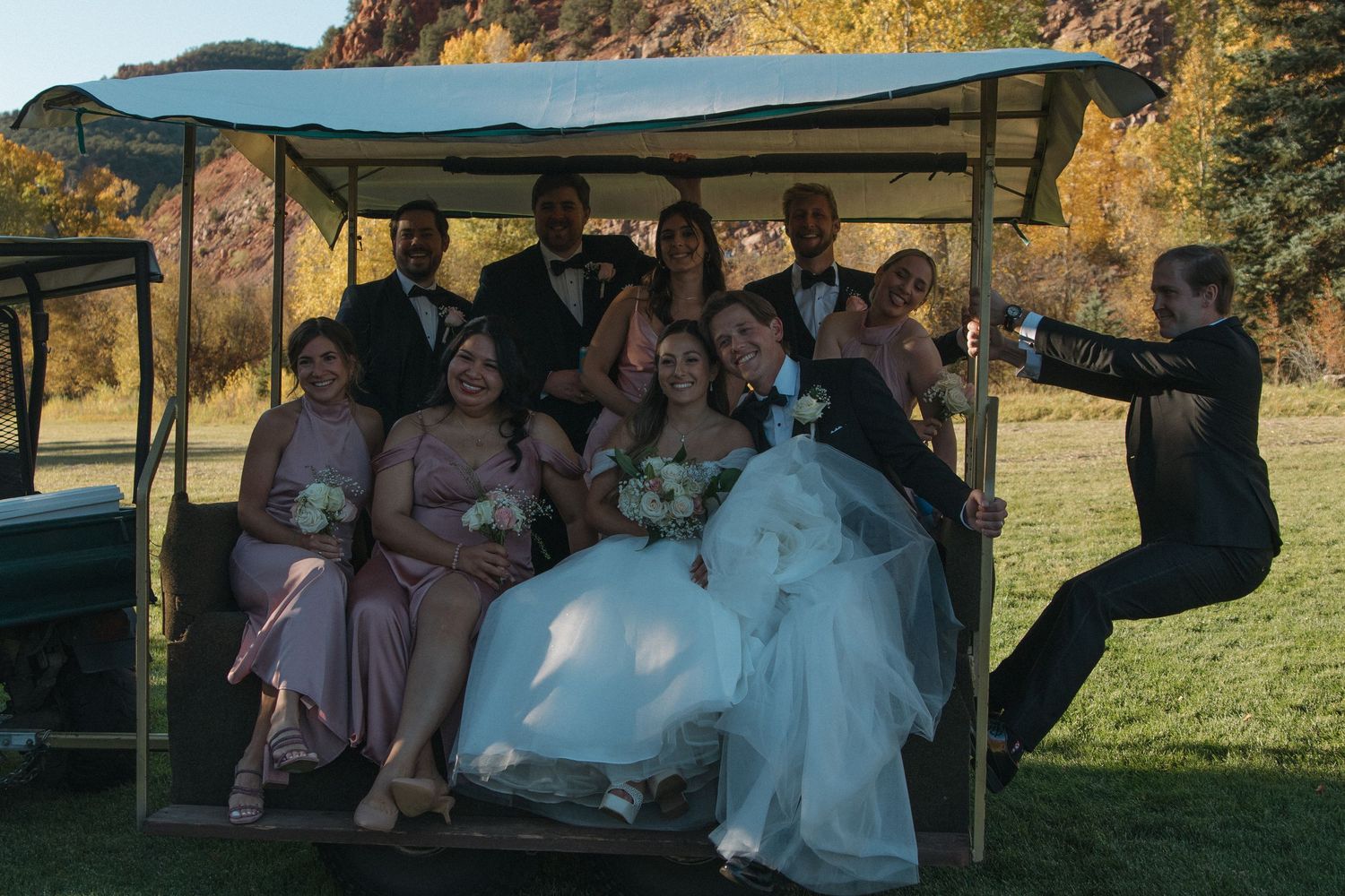 Wedding celebration under an outdoor pavilion with guests gathered at sunset.