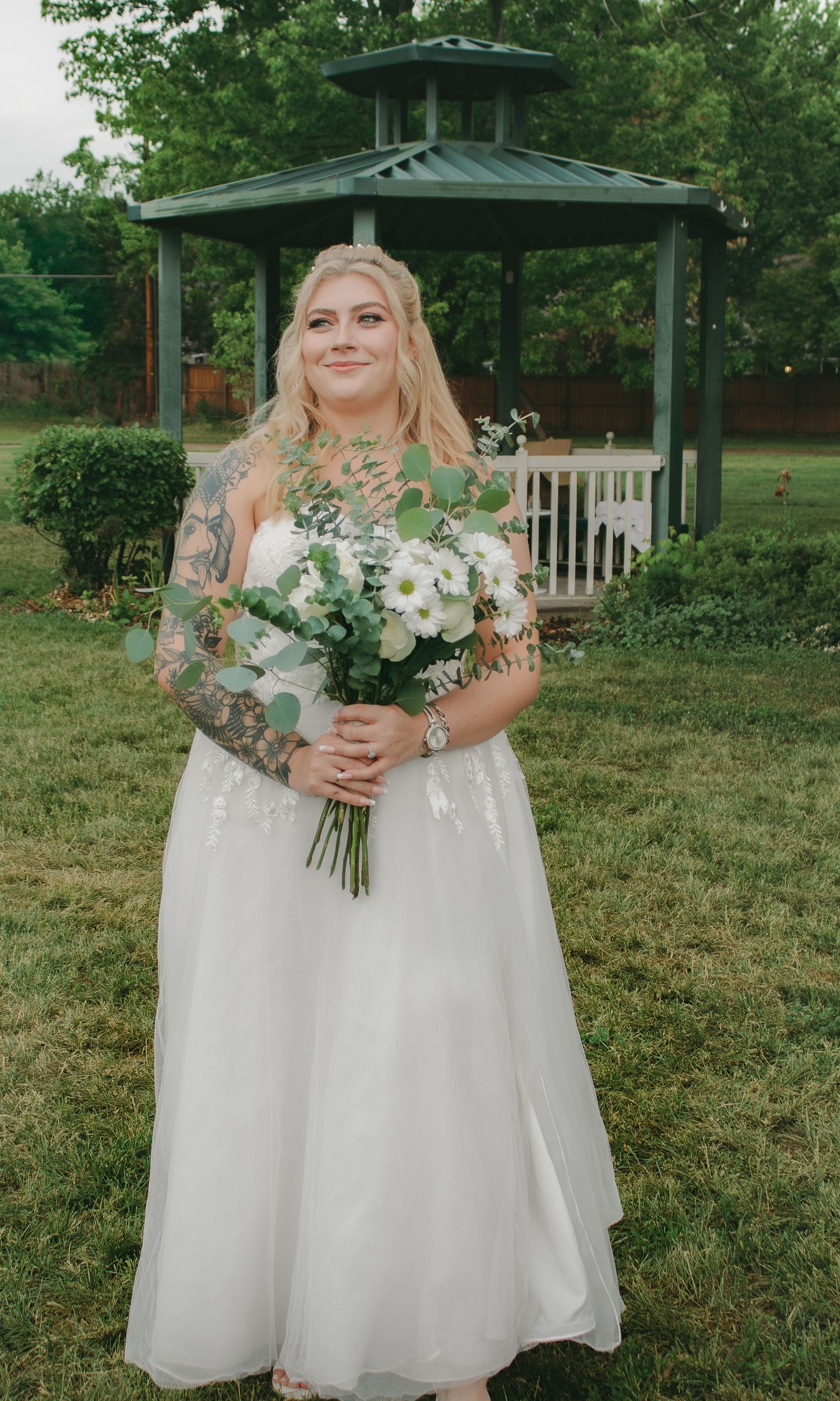 A white wedding gown with delicate lace details and a beautiful bouquet of white flowers and greenery.