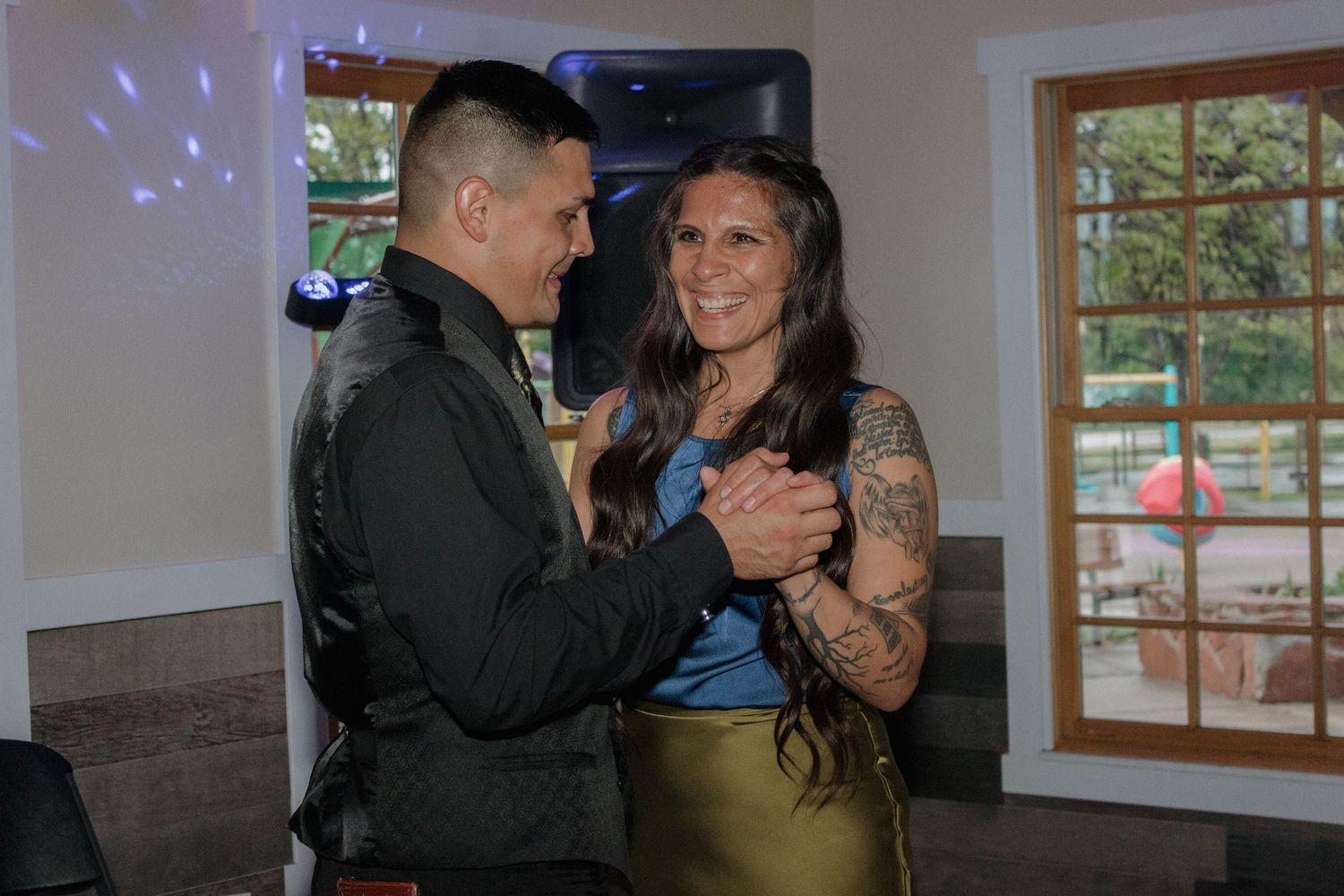 Blue disco lights illuminate a wedding reception venue as a couple dances together.