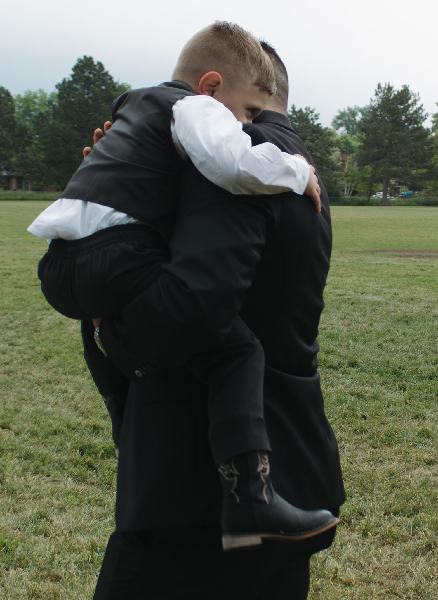 Couple embraces while wearing formal black and white attire in an outdoor setting.