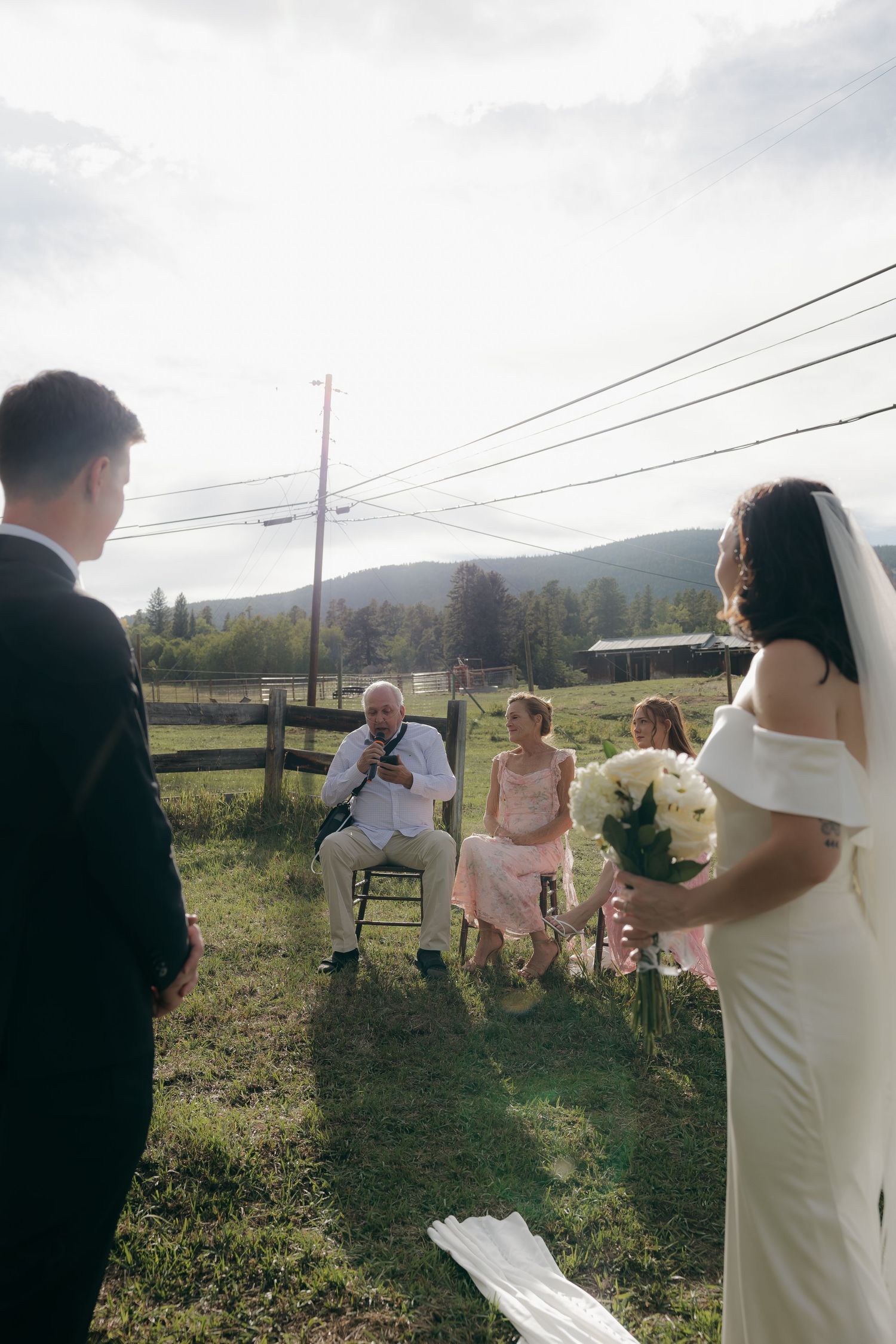 Intimate outdoor elopement ceremony with small group of guests in a mountain field.