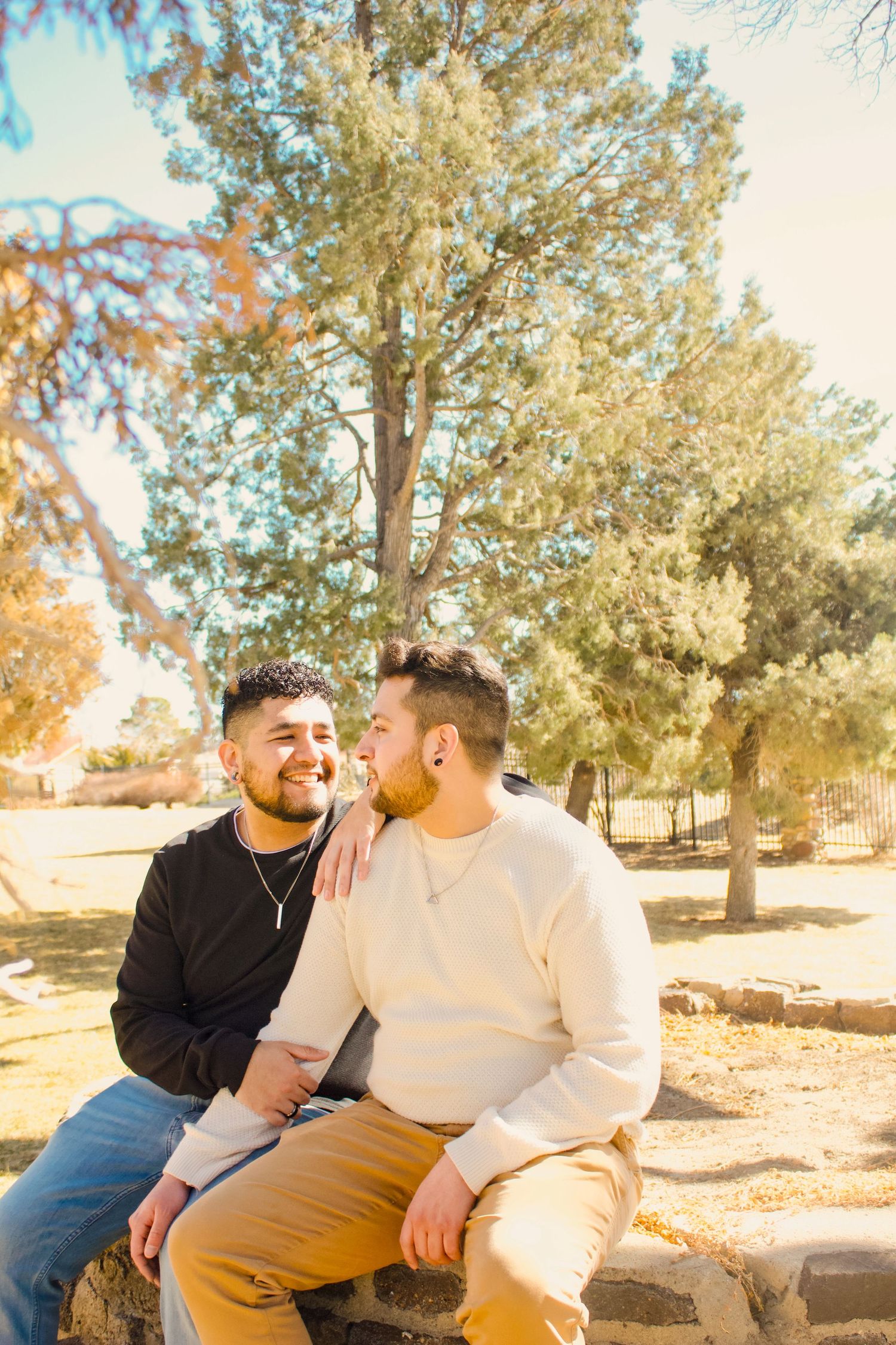 A couple sharing a joyful moment while sitting outdoors in a park setting.
