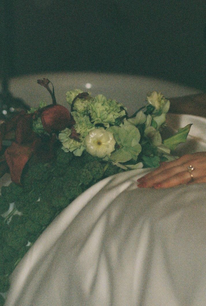 Close-up of floral decorations arranged on white fabric with red and cream blooms.