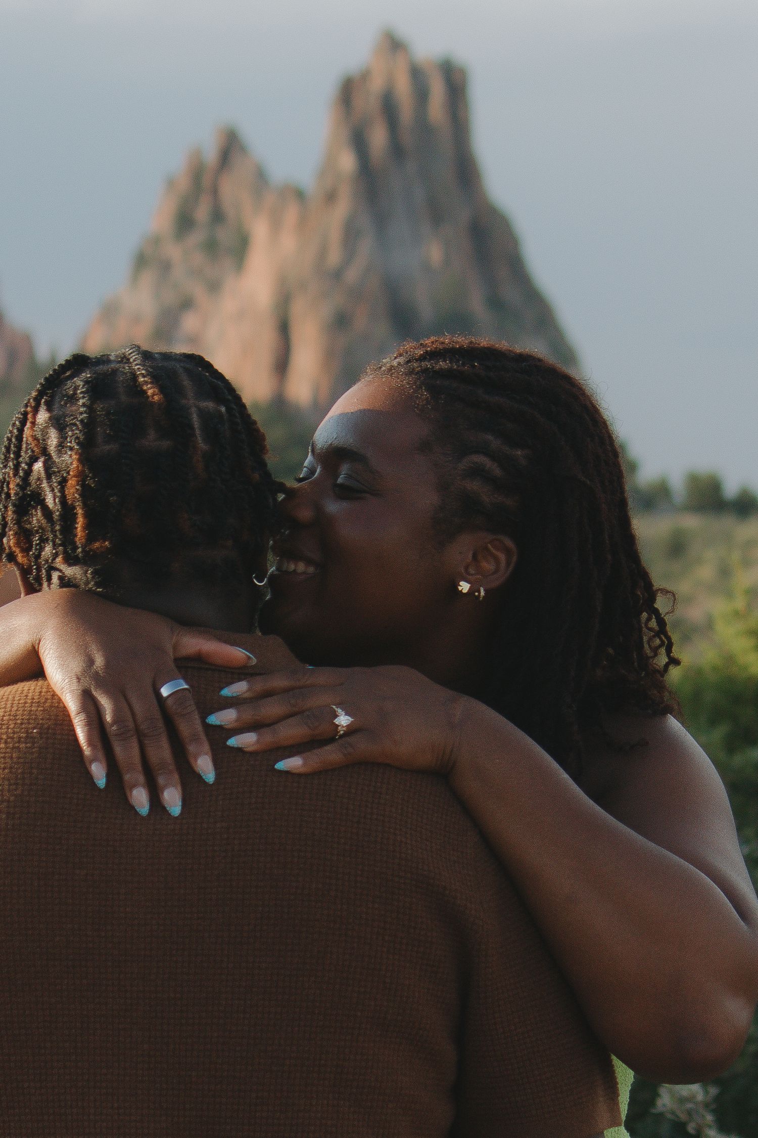 A tender embrace captured against dramatic rock formations during golden hour.