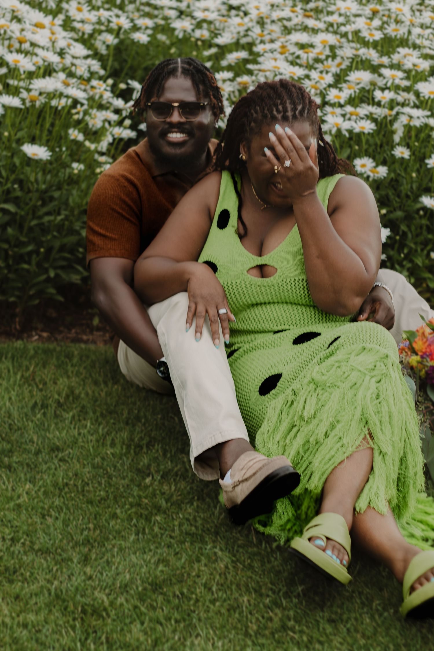 Candid photos of a couple lounging on grass with one wearing a lime green polka dot dress during a sunny day.