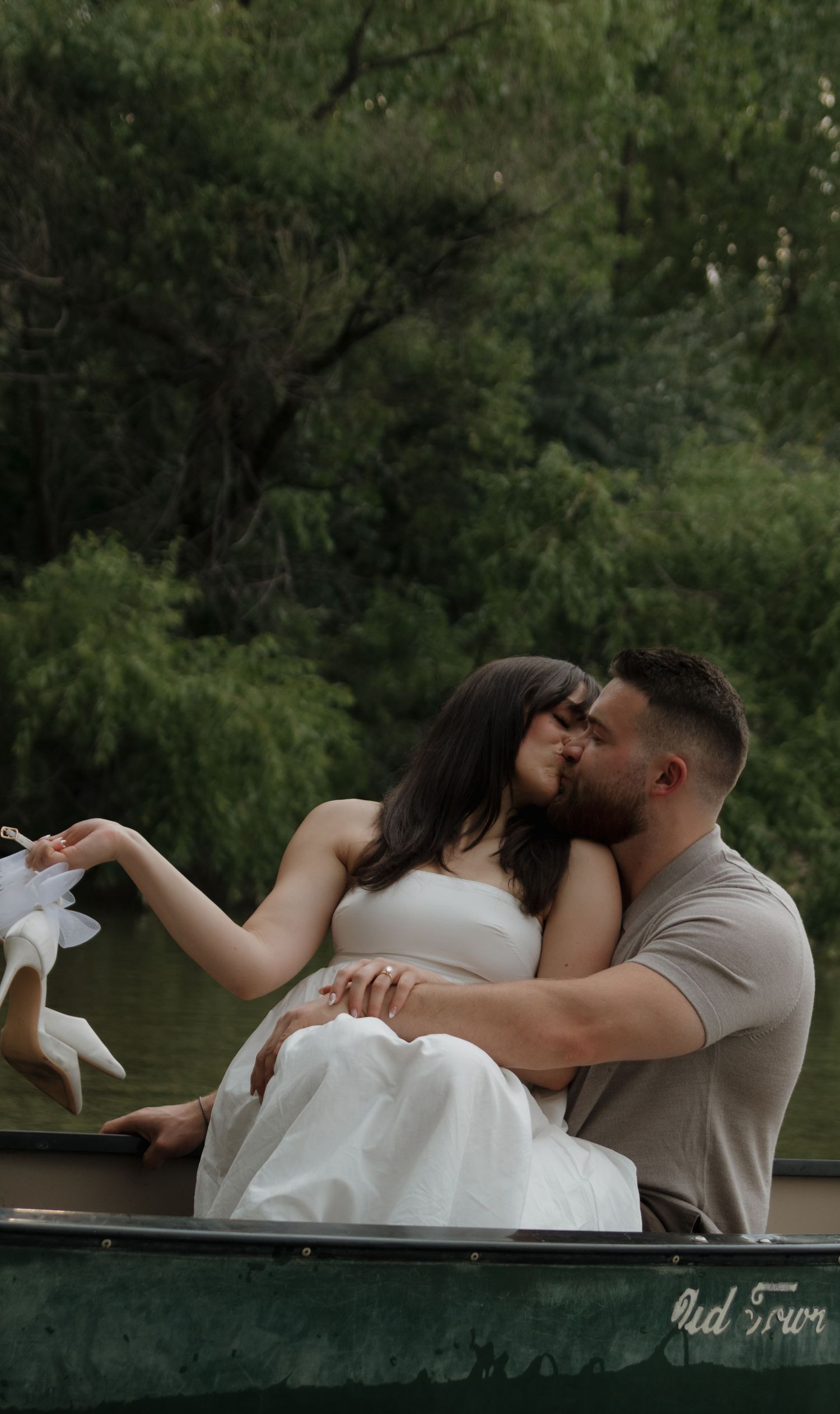 Couple shares tender moments while lounging in a canoe surrounded by lush greenery.