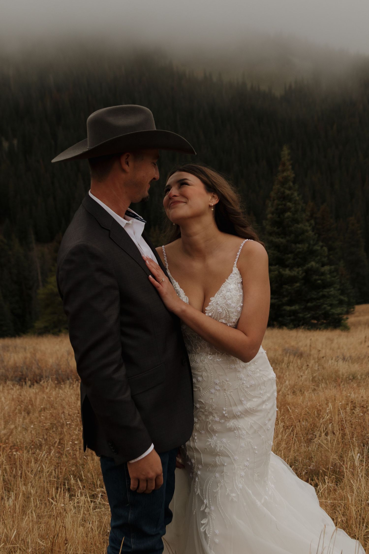 A tender moment between newlyweds in a mountain field during golden hour.