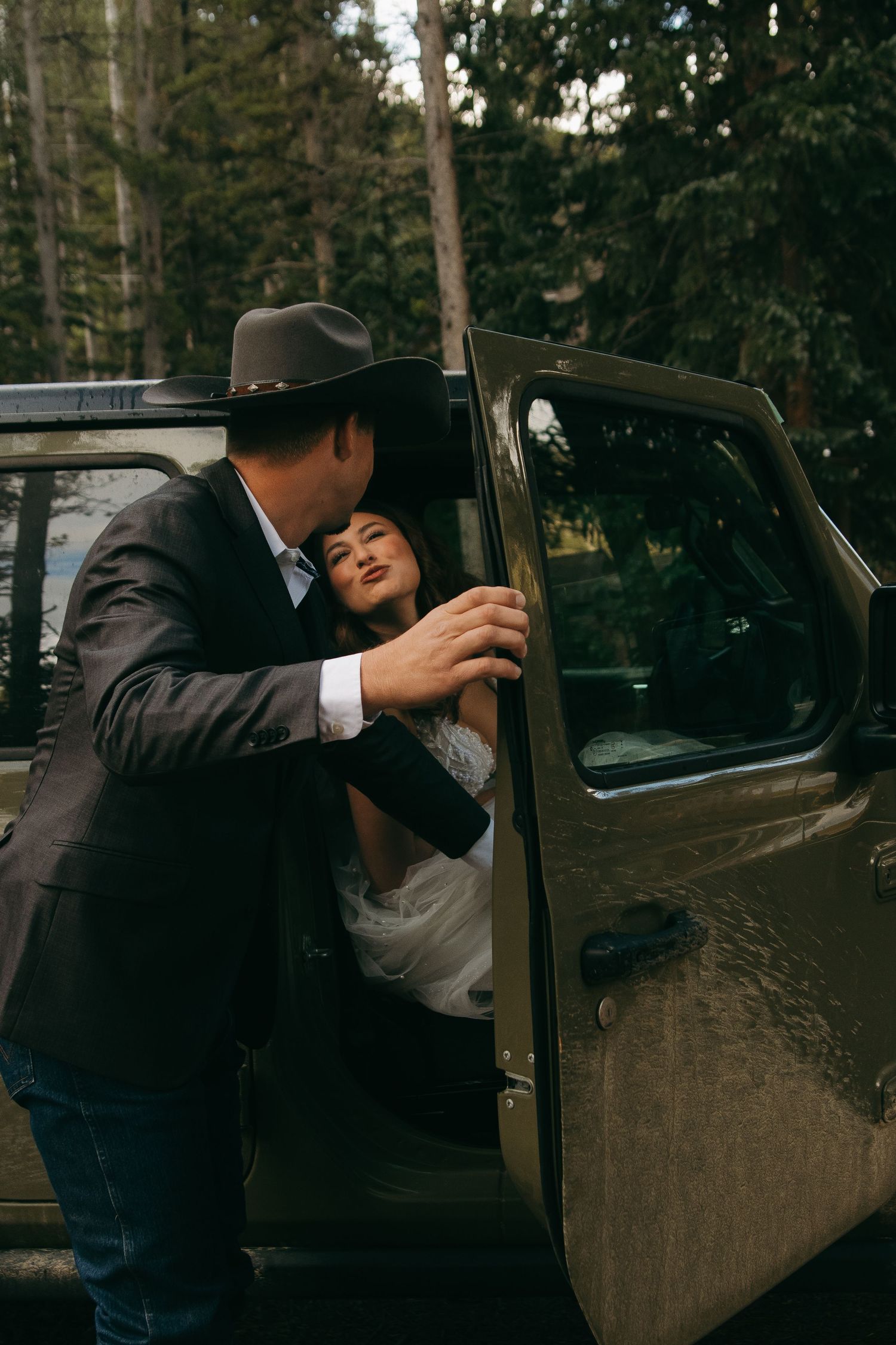 A couple shares an intimate moment near a vintage car door.