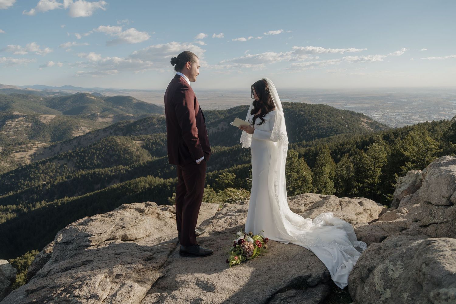 Bride and groom exchange vows on rocky mountain summit with breathtaking valley views at elopement.
