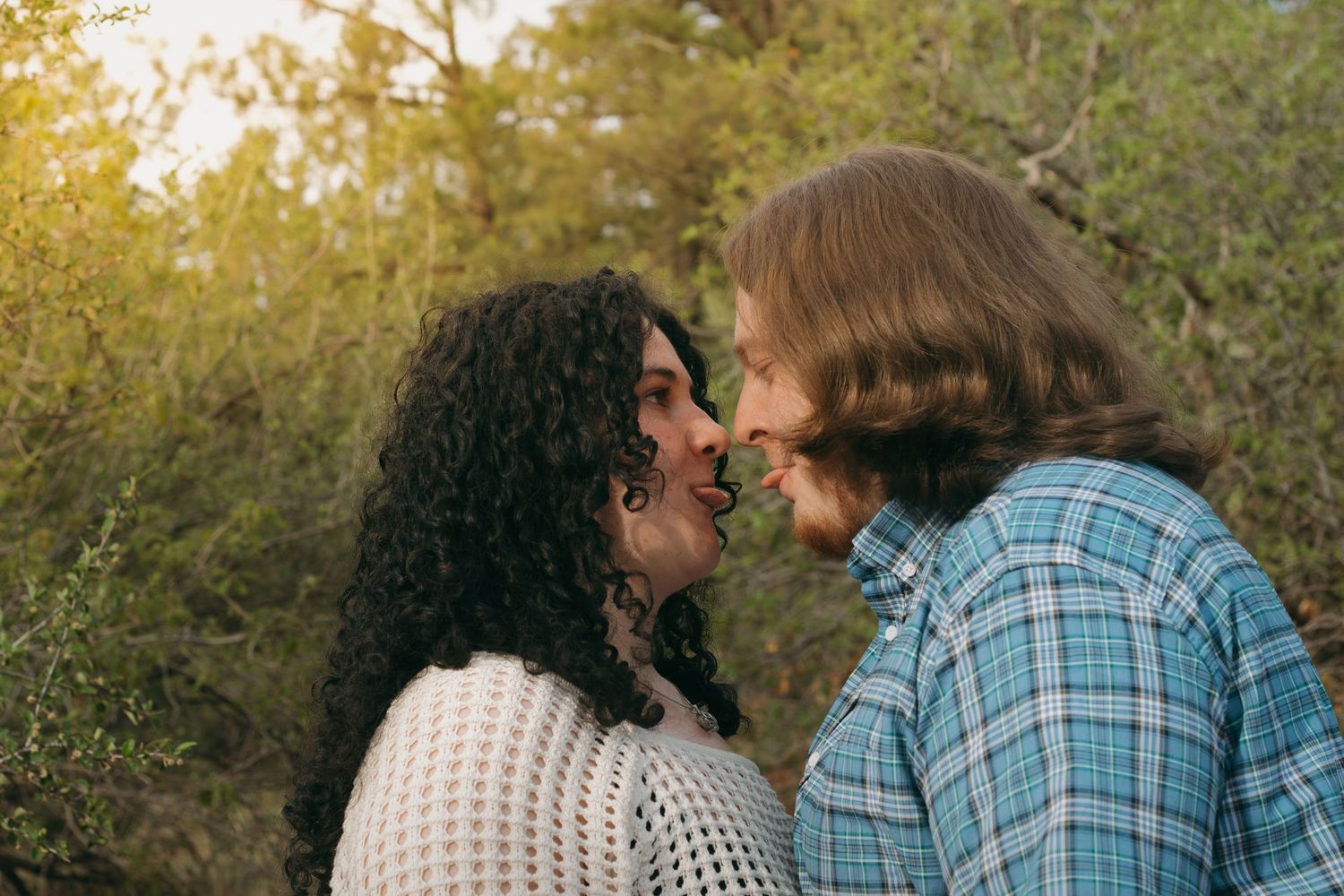 Intimate portrait of couple in soft golden light against natural backdrop.