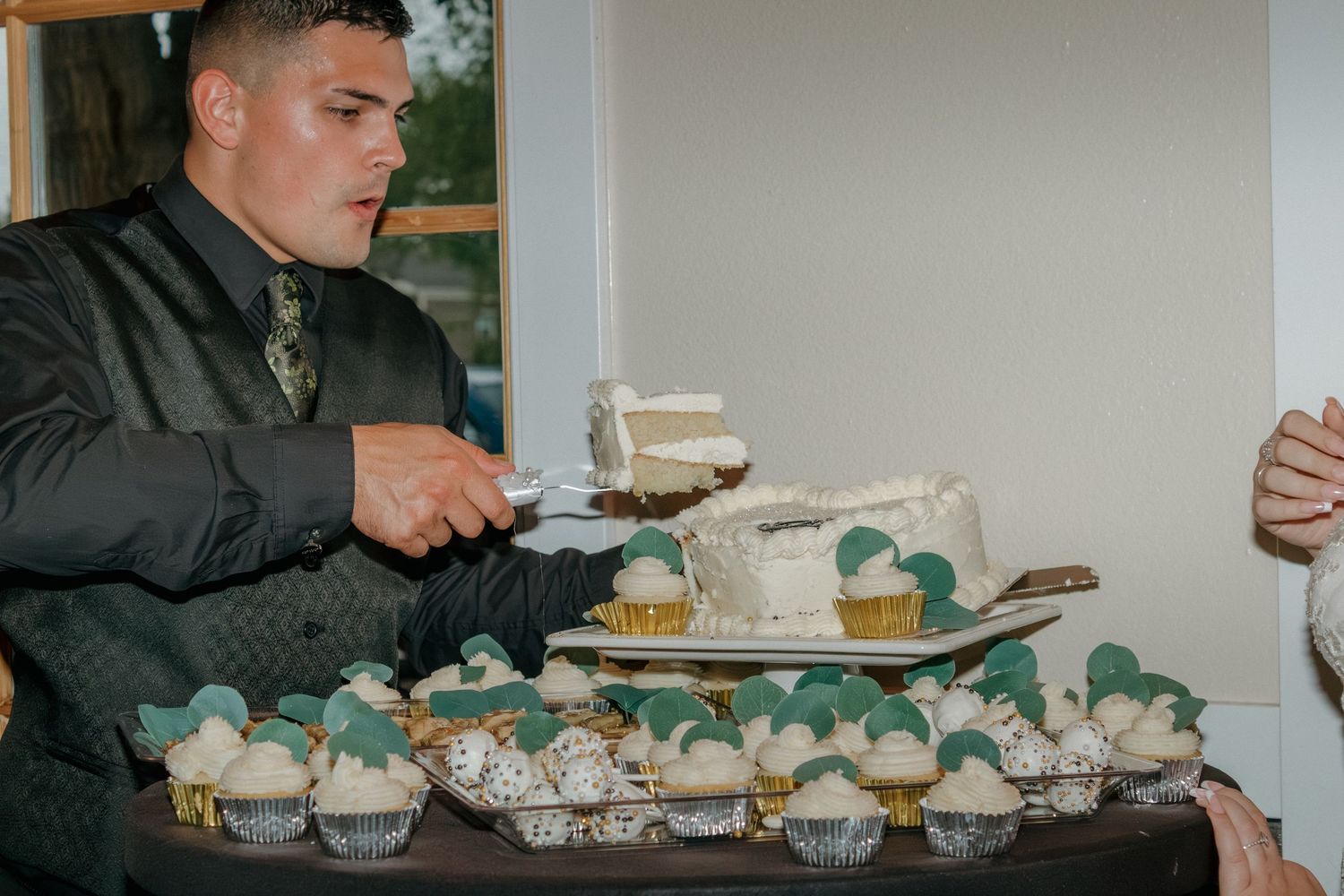 Wedding dessert table with elegant display of treats and greenery decorations.