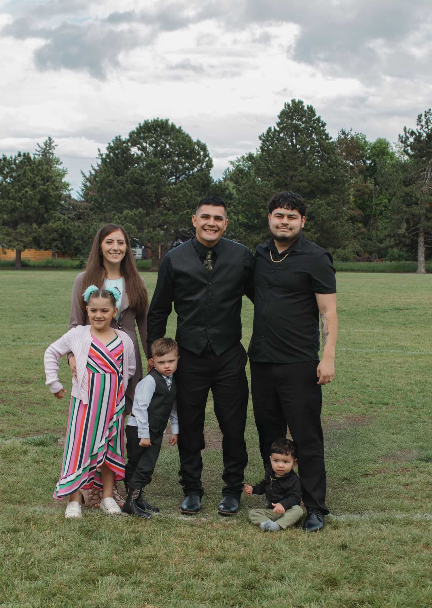Group portrait of family members in formal attire on grassy field.