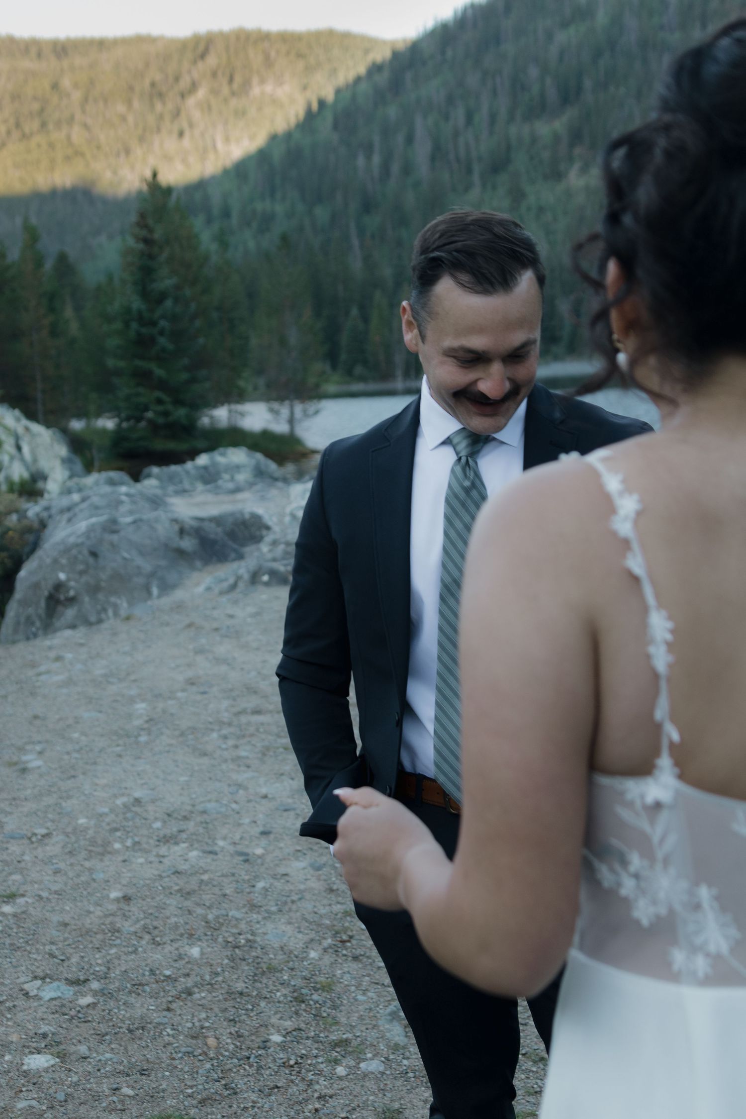 A couple sharing an intimate moment during their mountain wedding ceremony against a backdrop of evergreen forests.
