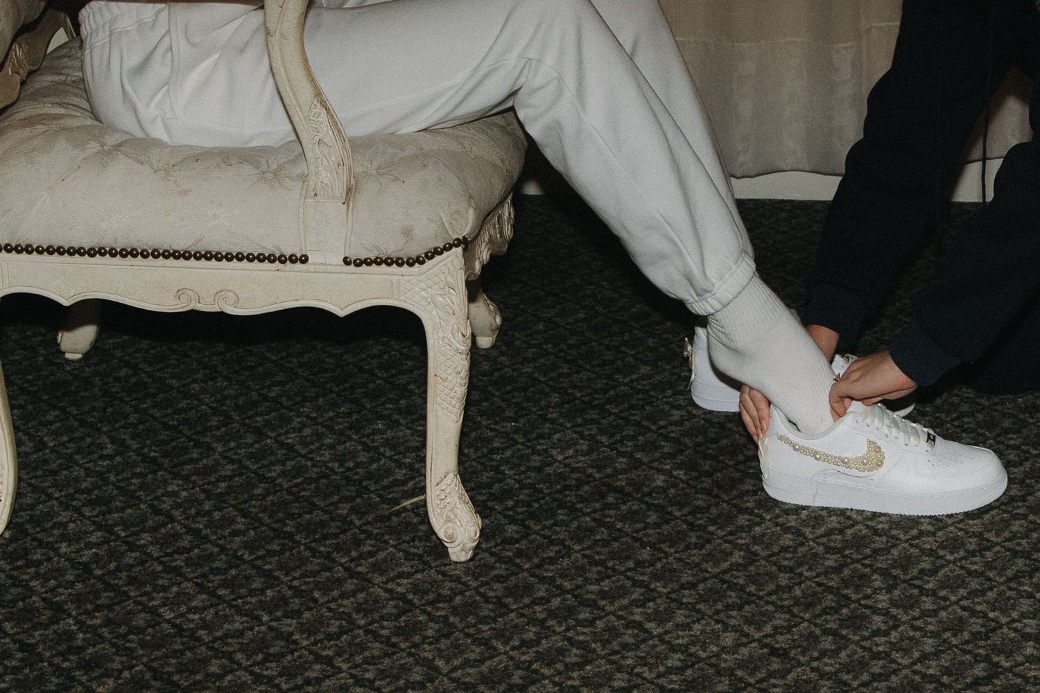 Close-up detail shot of formal wedding attire and shoes on a patterned carpet.