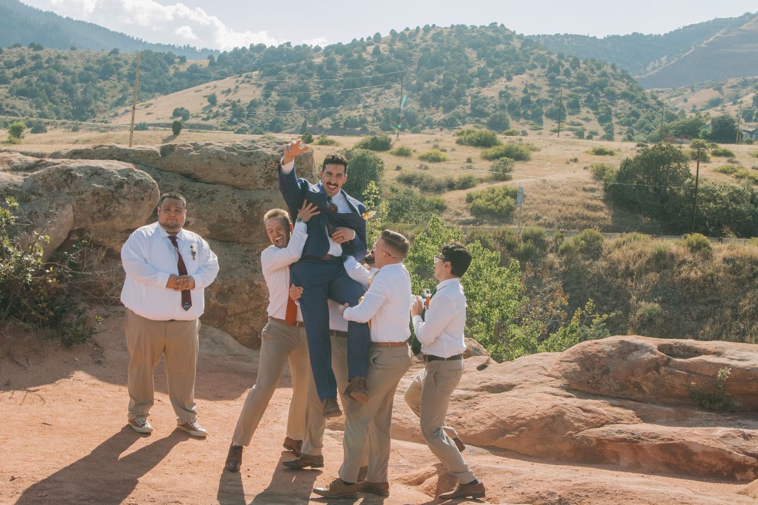 Group enjoys scenic mountain views during wedding celebration on rocky overlook.
