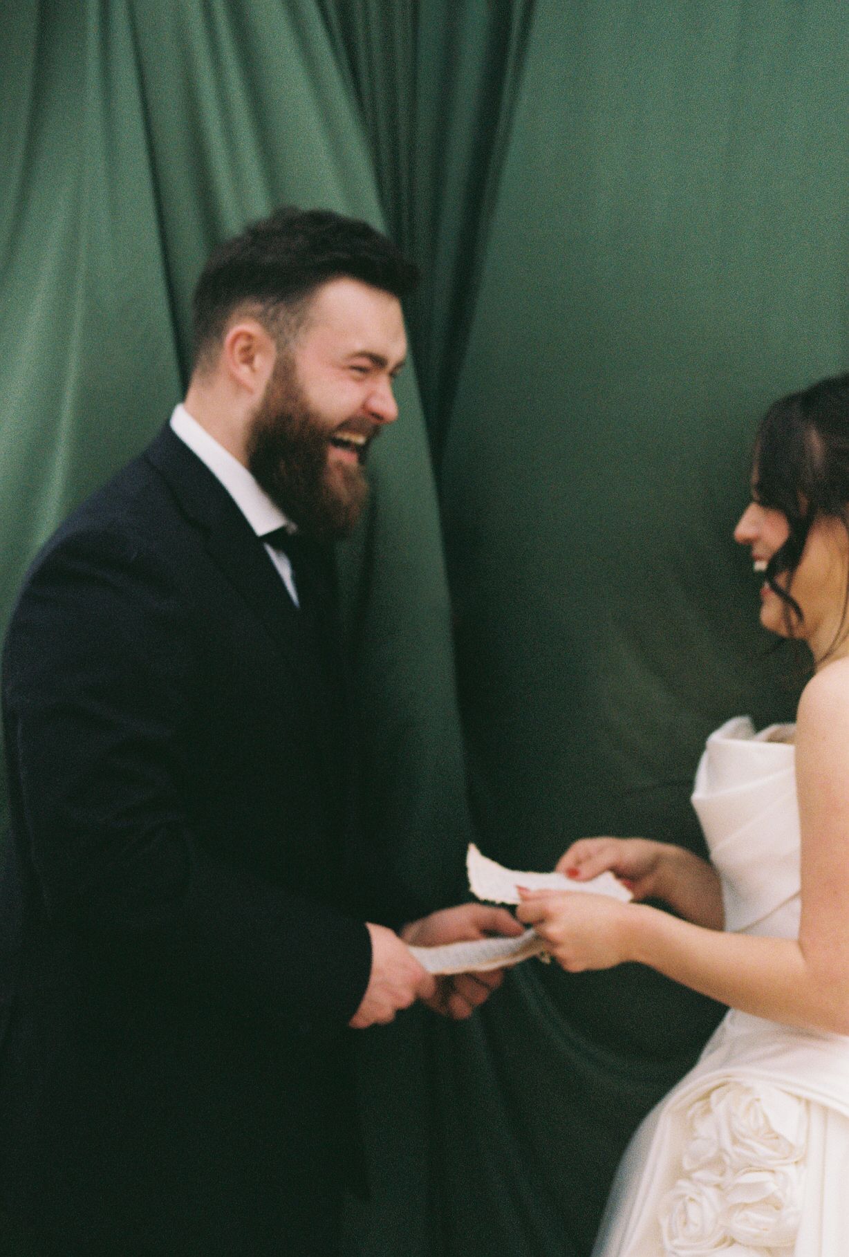 Couple in formal attire exchanging notes or letters against a green curtain backdrop in a sequence of candid moments.