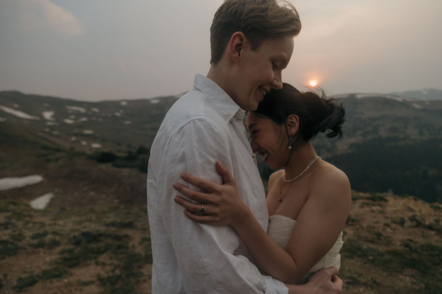 Couple embraces tenderly at golden sunset on a mountain ridge during their intimate outdoor elopement.