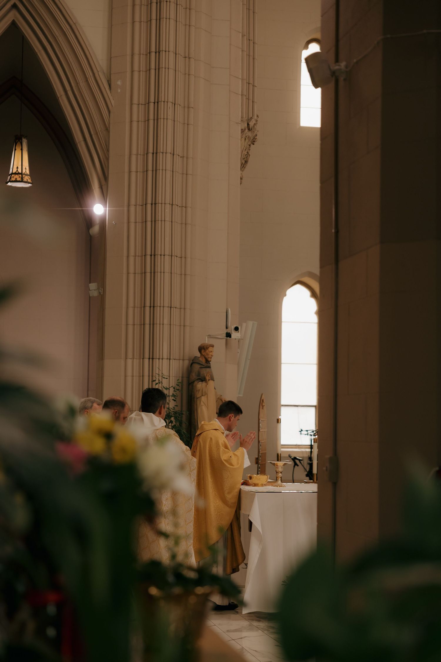Priest in gold vestments performs Catholic wedding Mass at ornate altar.