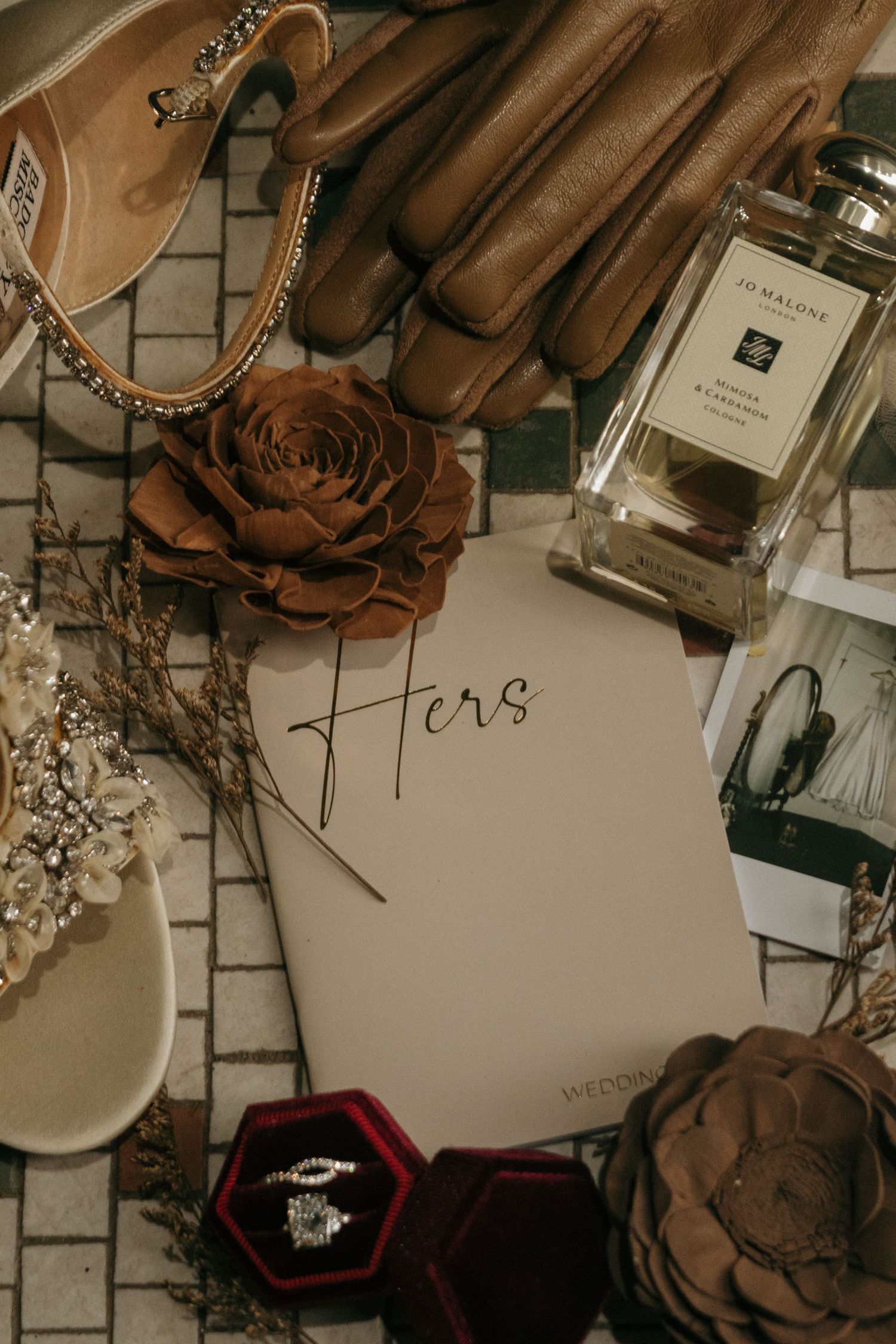A collection of wedding details including jewelry boxes, flowers, and calligraphy on a neutral background.