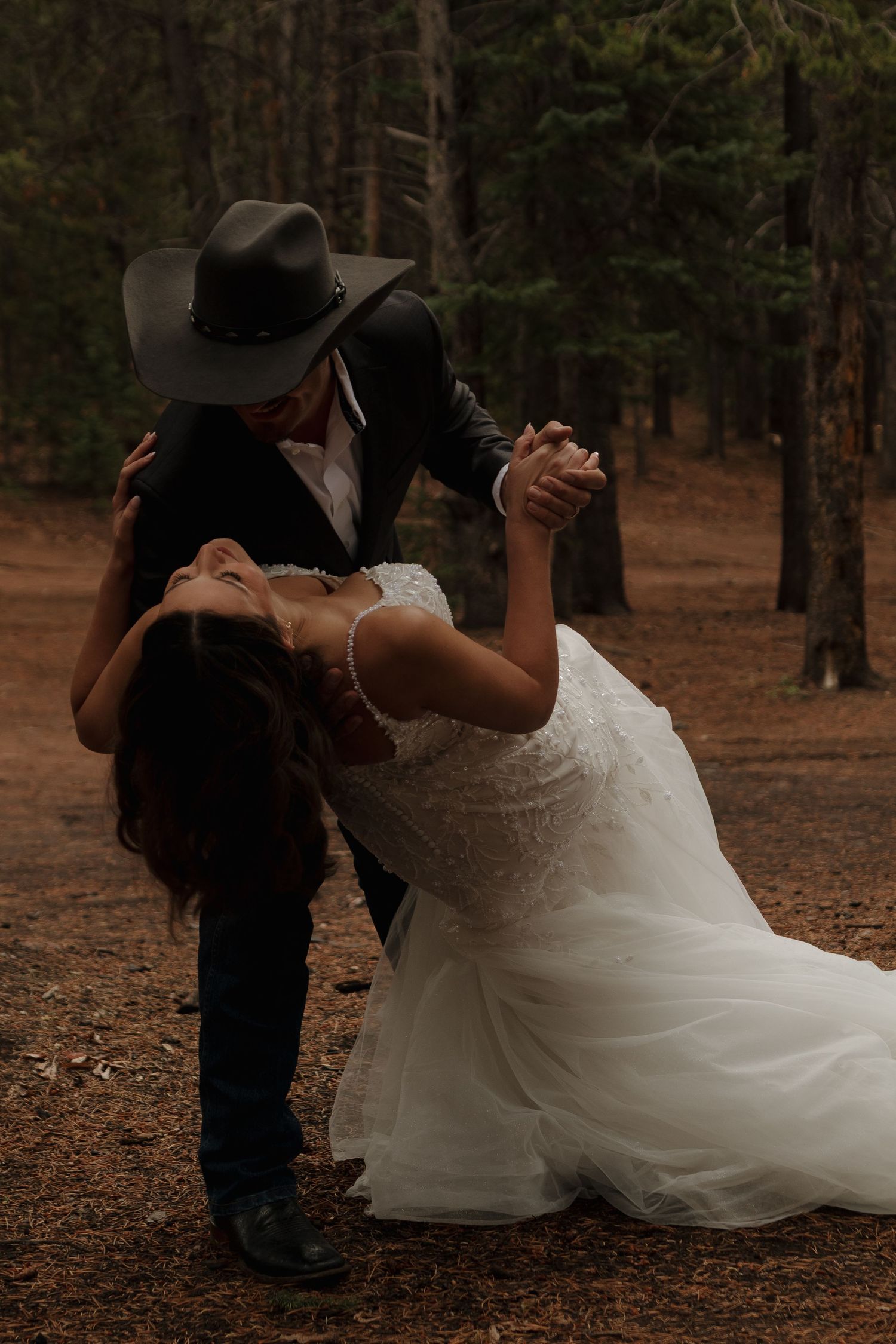 A romantic wedding dance sequence in a forest setting with a flowing white dress and cowboy hat.