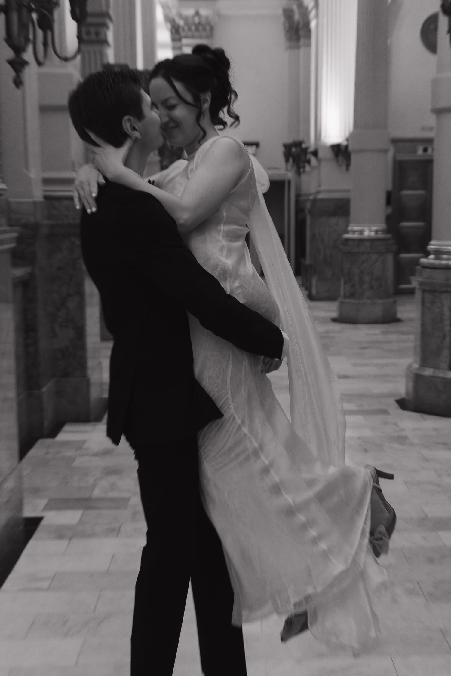 Couple dancing in an elegant hall with classical columns and marble details.