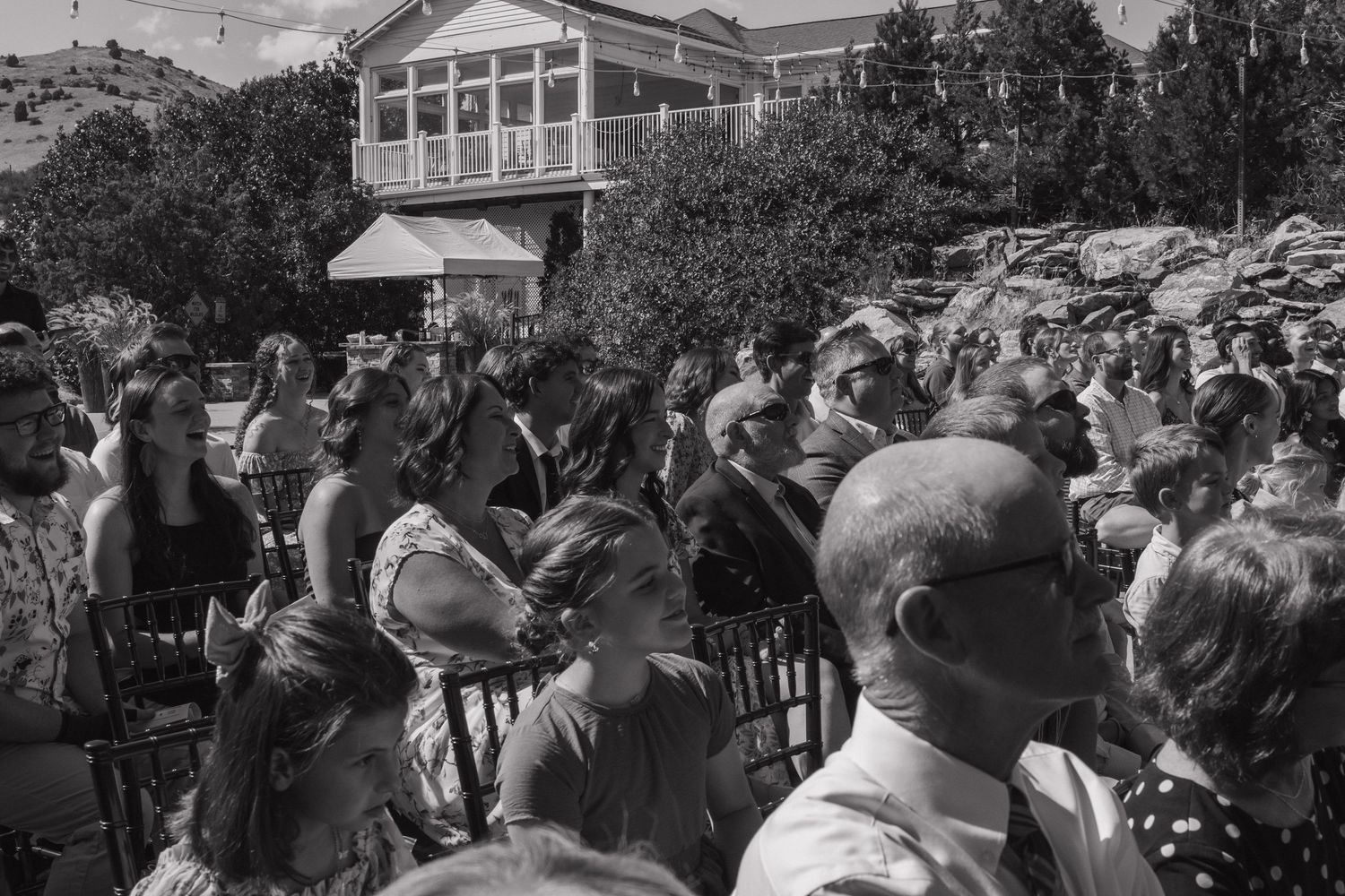 Wedding guests seated in rows watching an outdoor ceremony.
