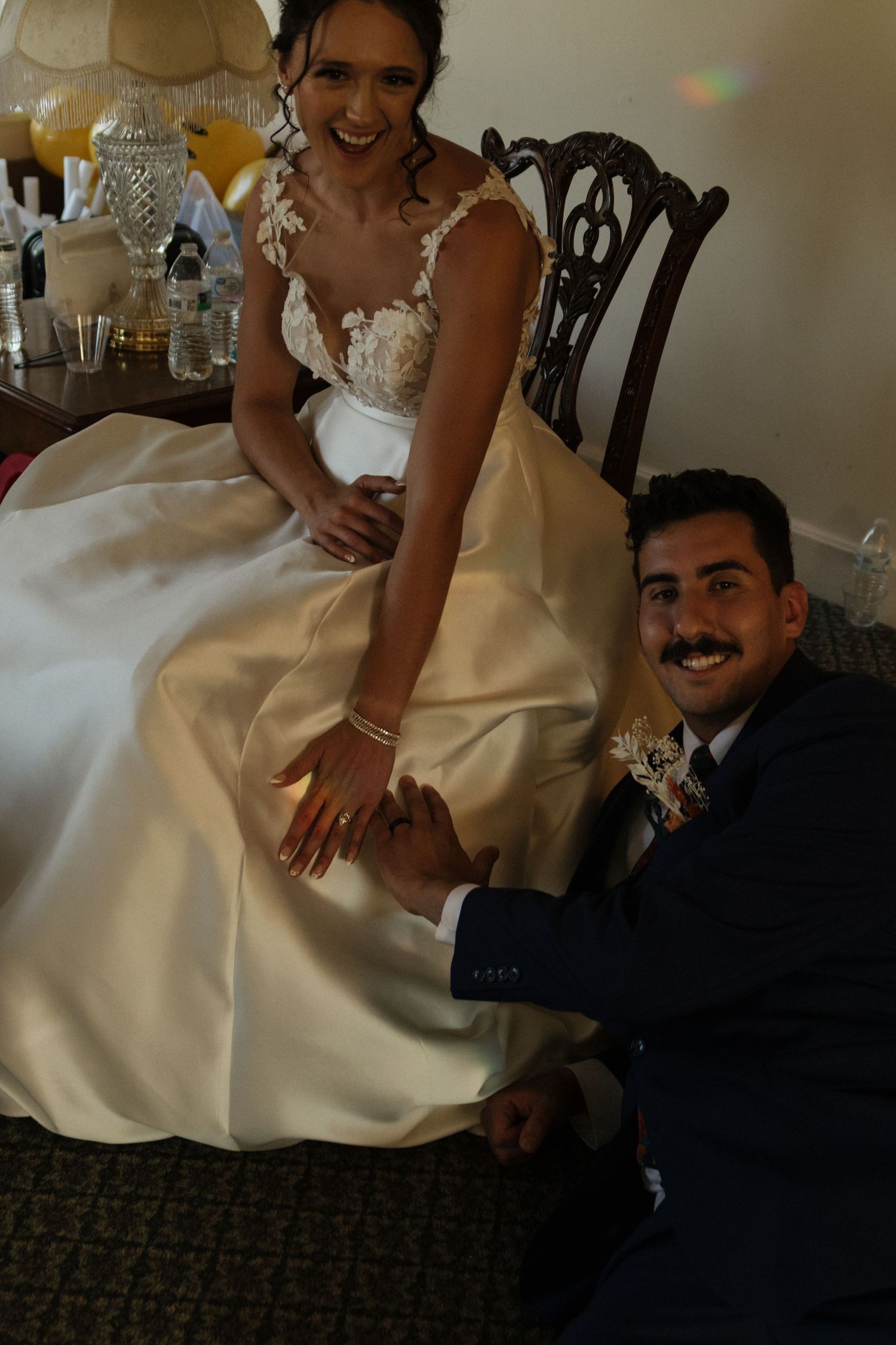 Intimate wedding reception moment with couple seated in vintage chair.