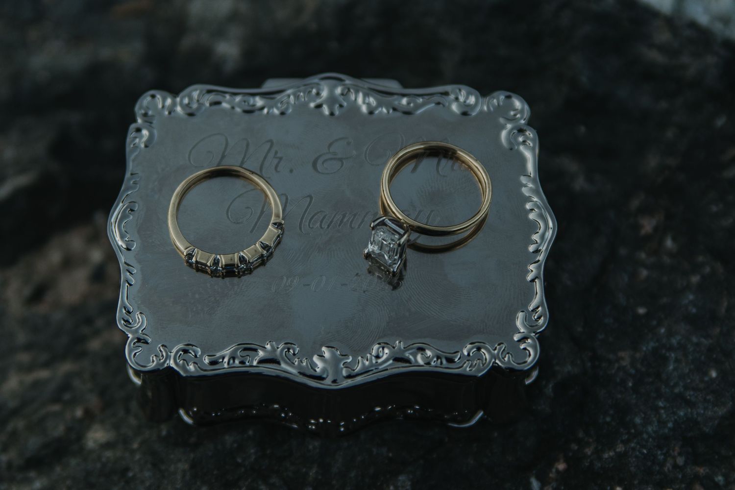 Close-up of elegant wedding rings displayed on ornate silver platter.