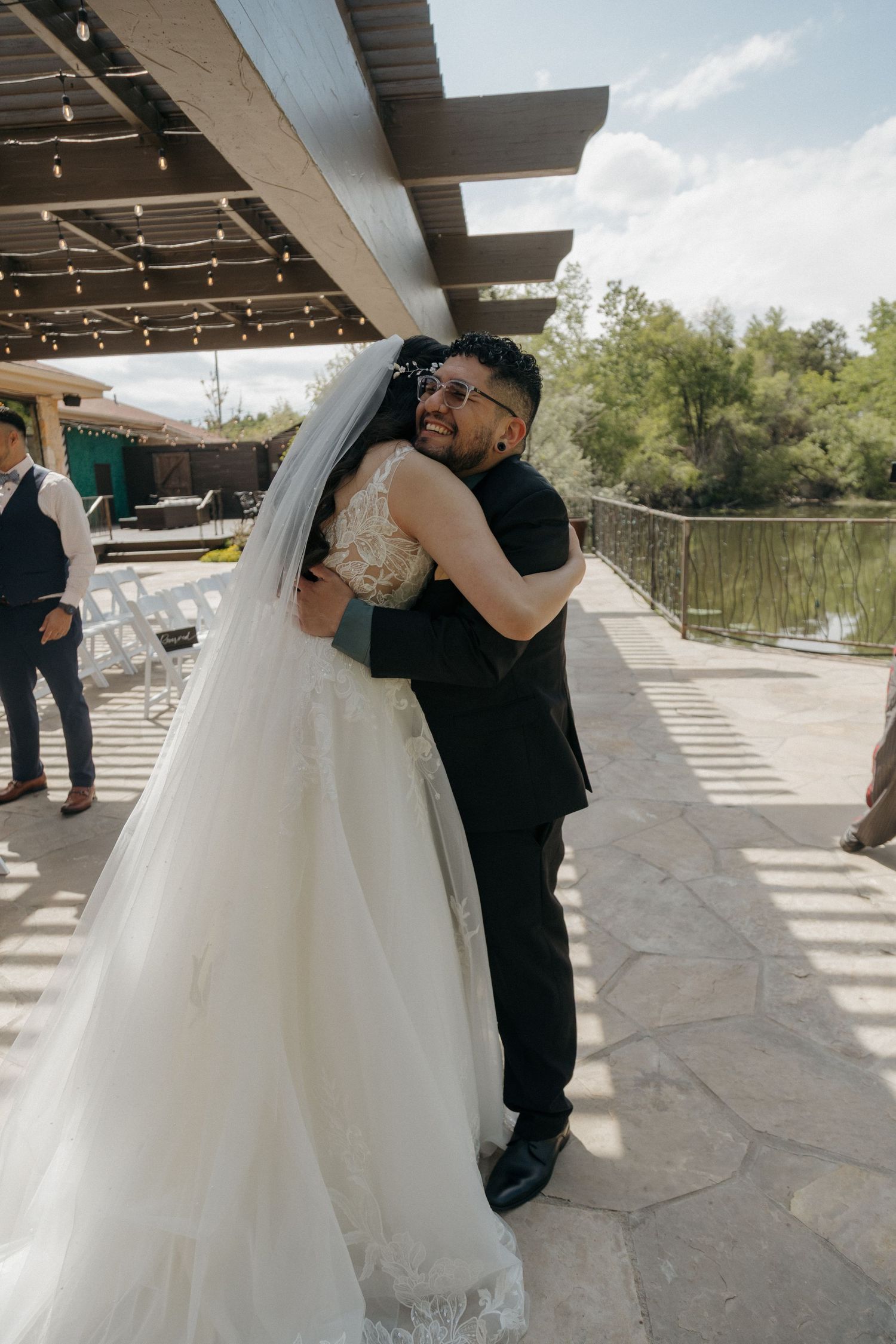 Emotional bride and groom sharing a heartfelt hug on outdoor wedding venue patio.