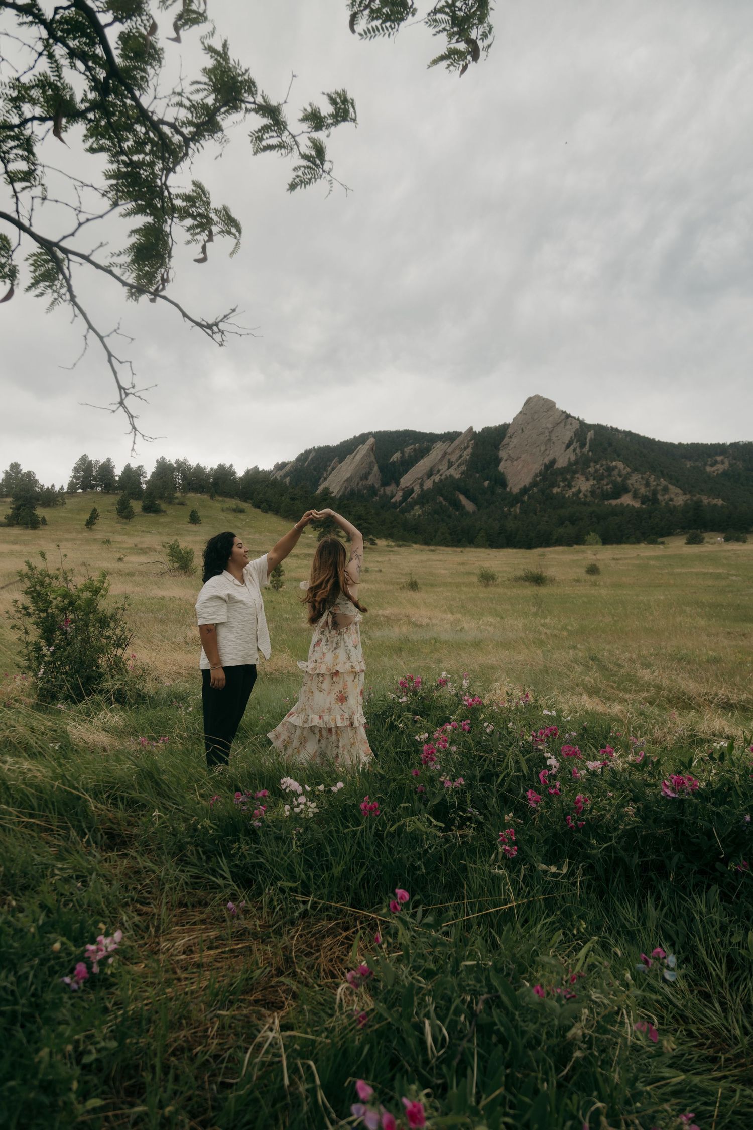 Couple dancing in a wildflower meadow with the Boulder Flatirons rocky mountains in the background.