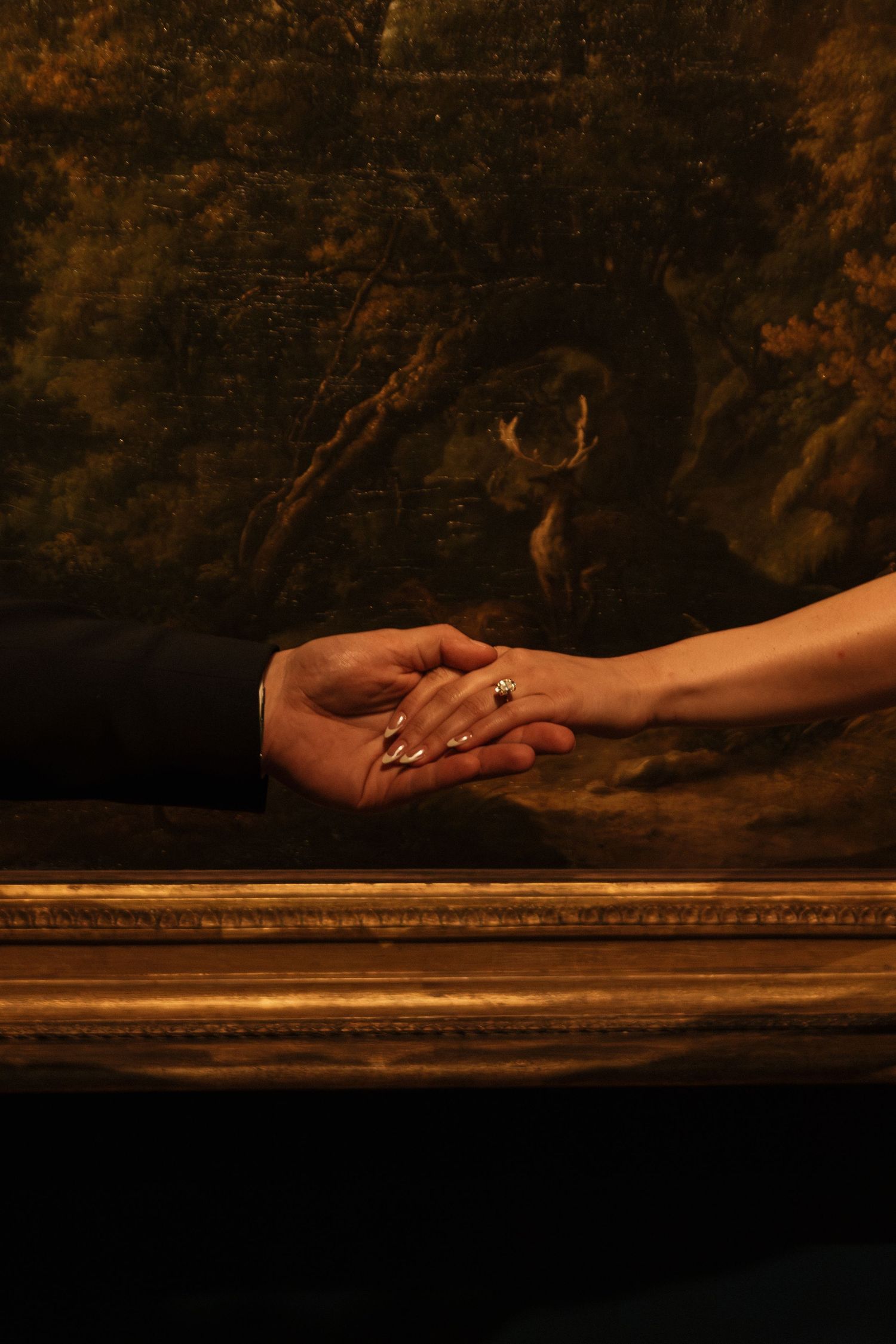 Two hands reaching across a dark wooden surface in dramatic lighting against a textured background.