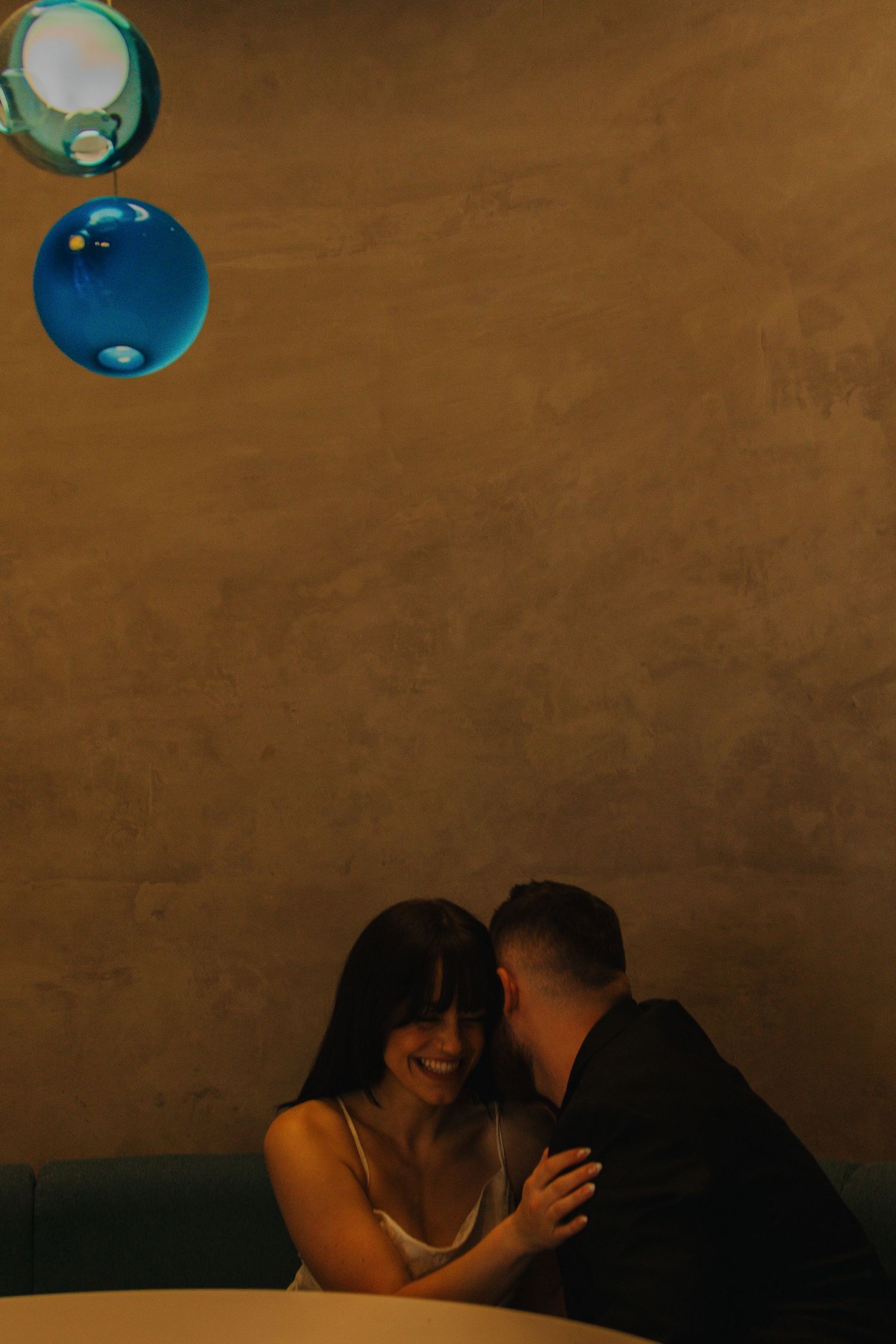 Intimate moment captured under blue pendant lights.