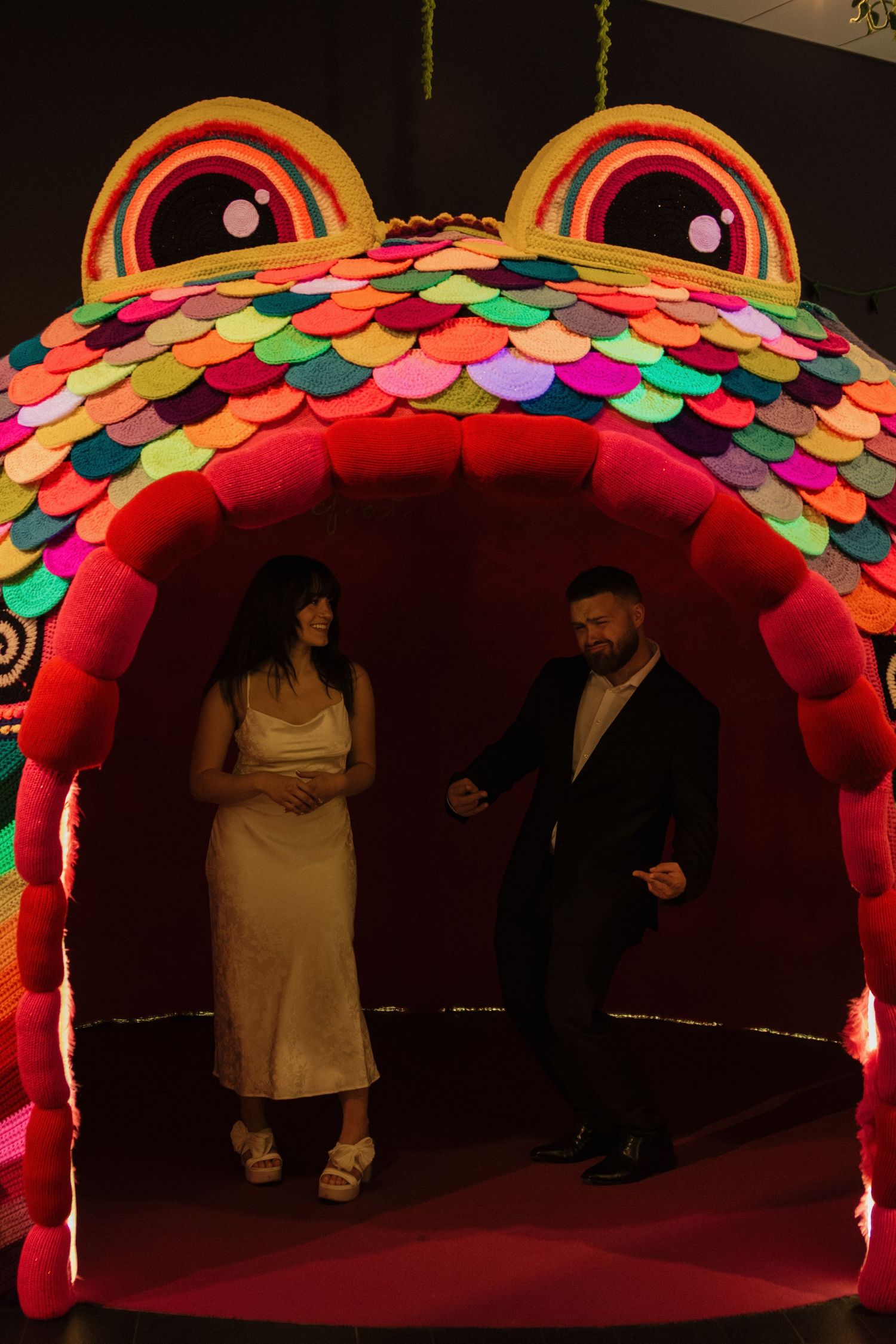 Colorful illuminated rainbow archway with people walking beneath during an event.