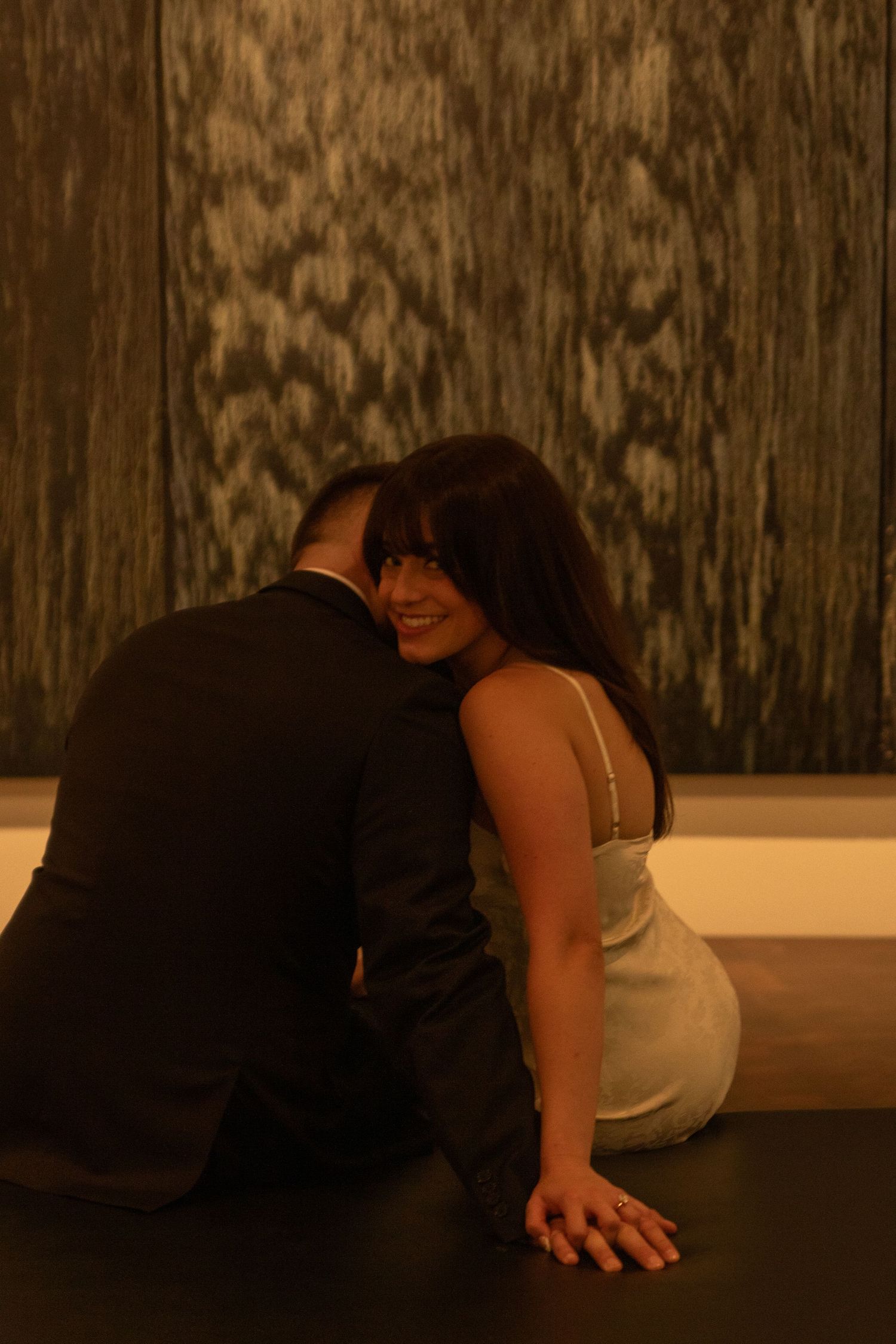 Intimate dance scene captured in warm lighting against textured wall background.