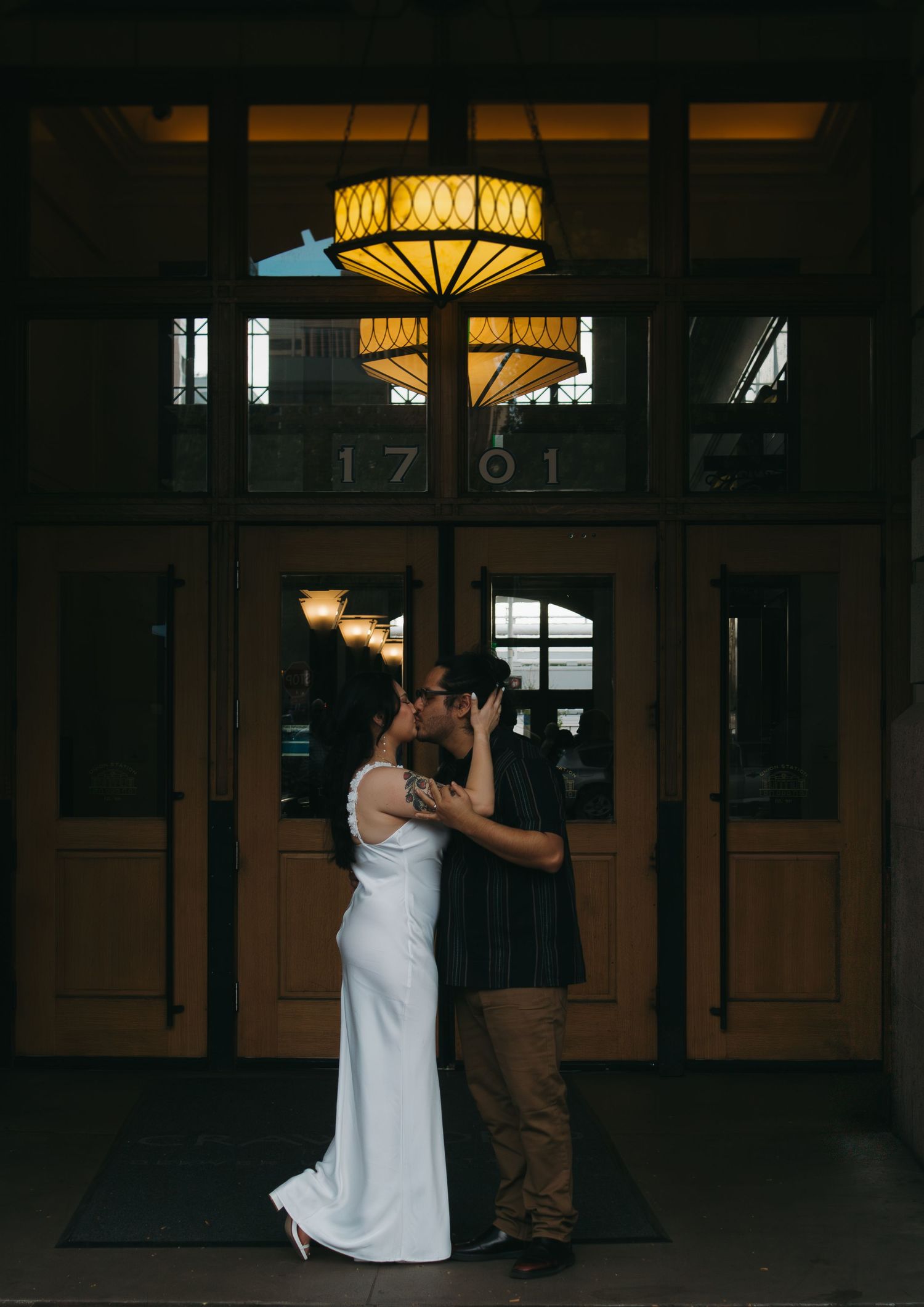 A romantic moment captured in a dimly lit venue with warm glowing lights overhead.